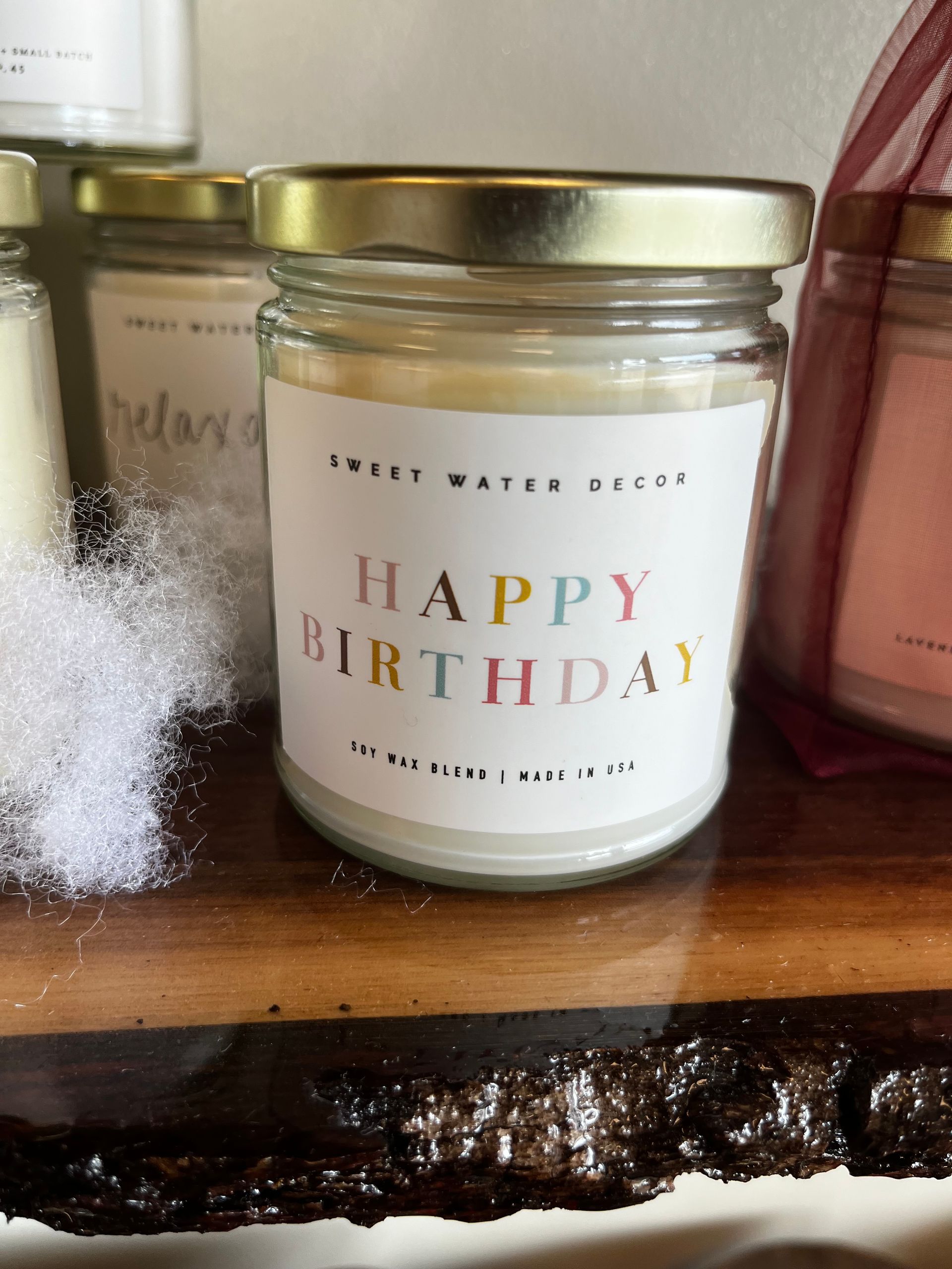 Birthday candle jar with gold lid and “Happy Birthday” label on a wooden shelf