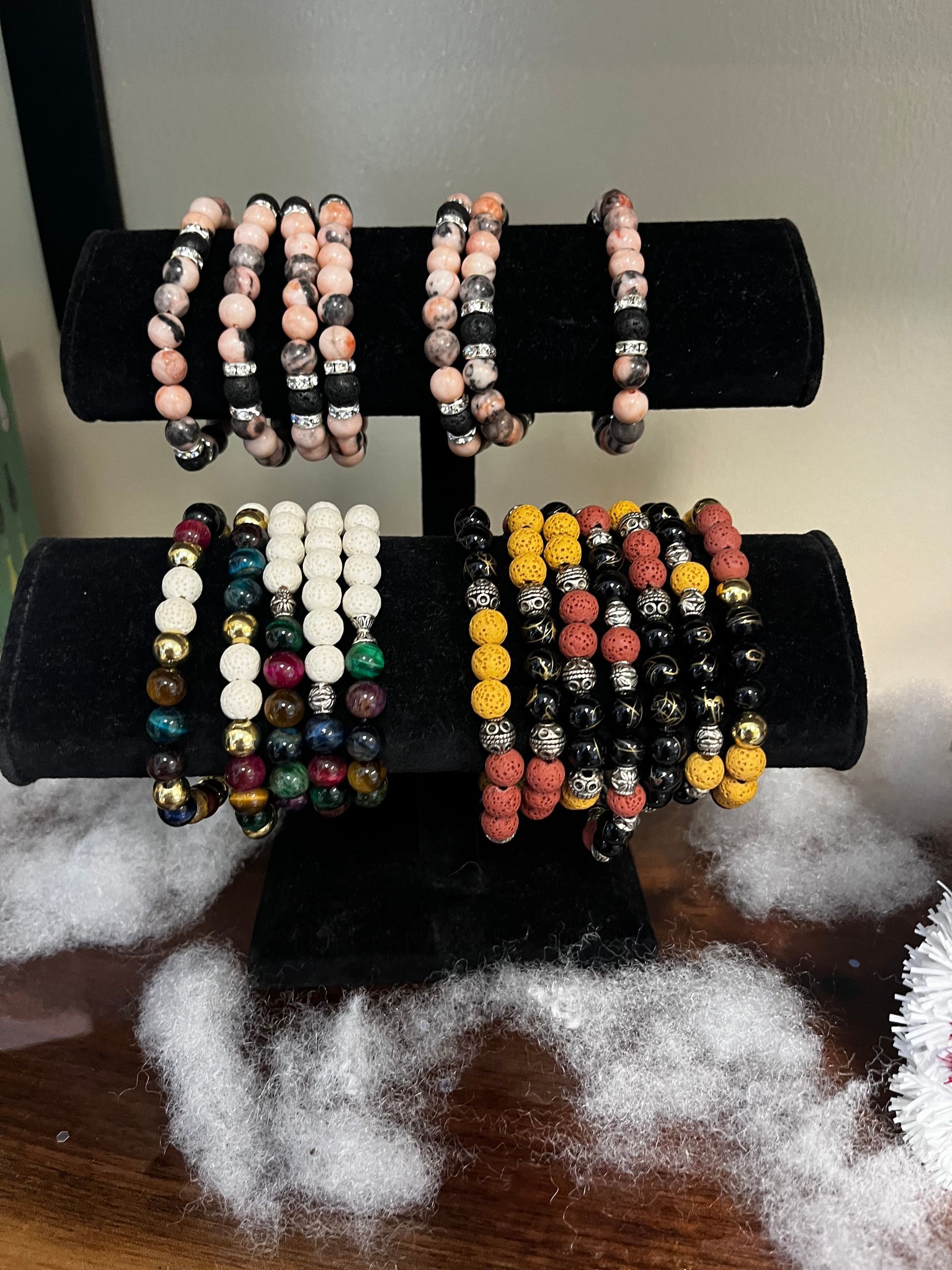Beaded bracelets displayed on black velvet stands with white cotton-like fill around them.
