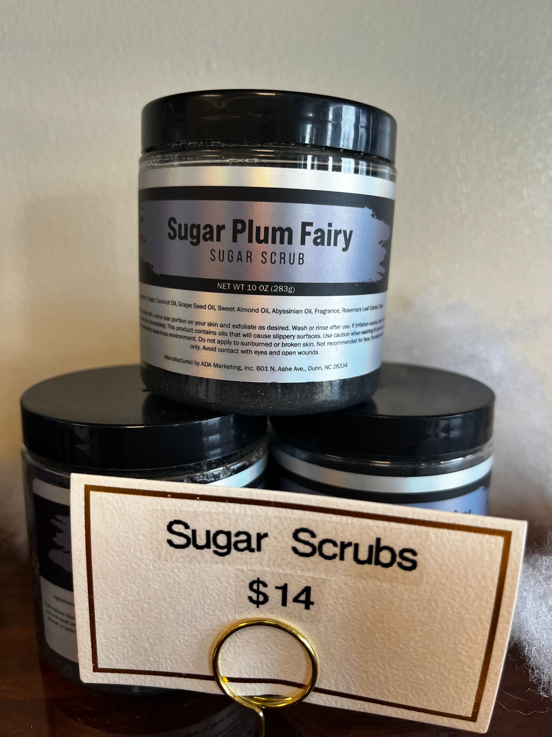 Two jars of Sugar Plum Fairy sugar scrubs with a $14 price sign in front