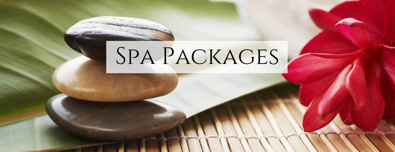 Spa packages banner with stacked stones, red flower, and bamboo mat