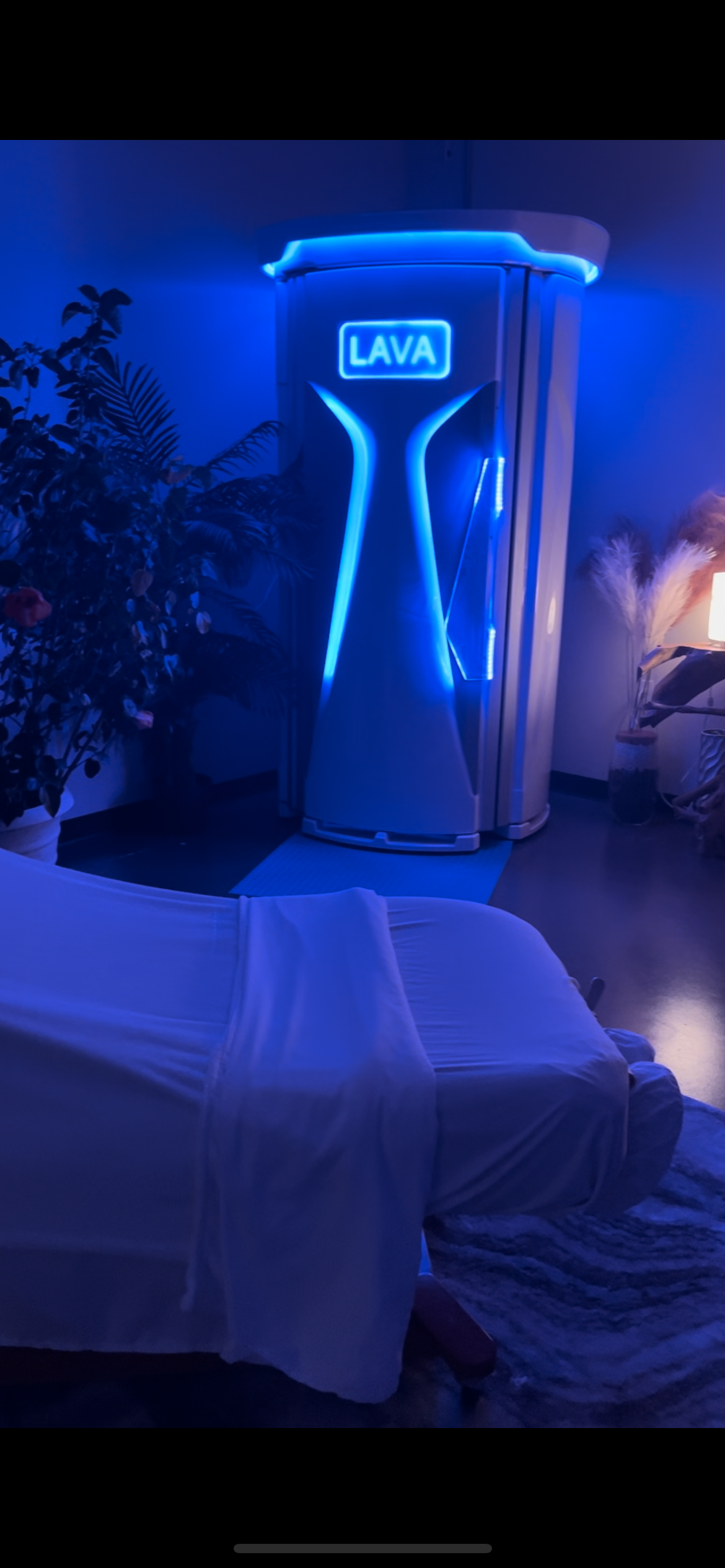 Blue neon lava cabinet glowing in a dim room behind a covered table