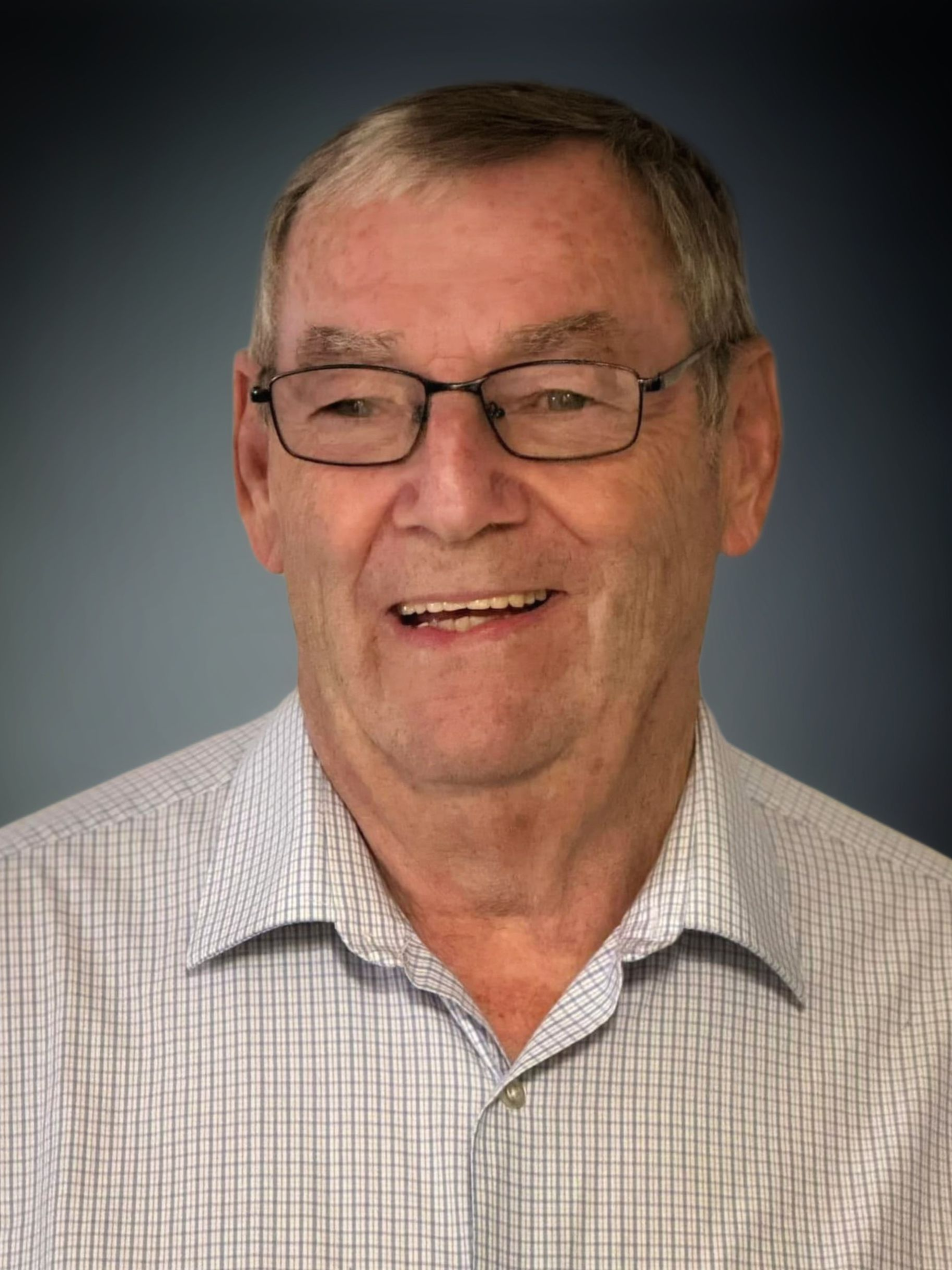 A man wearing glasses and a plaid shirt is smiling for the camera.