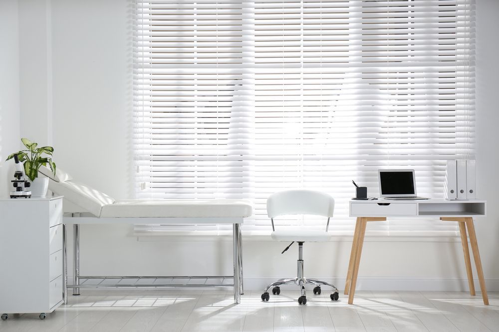 Bright minimalist office with white blinds, desk lamp, chair, and laptop on a wooden table — Rocky Commercial Cleaners In Berserker, QLD