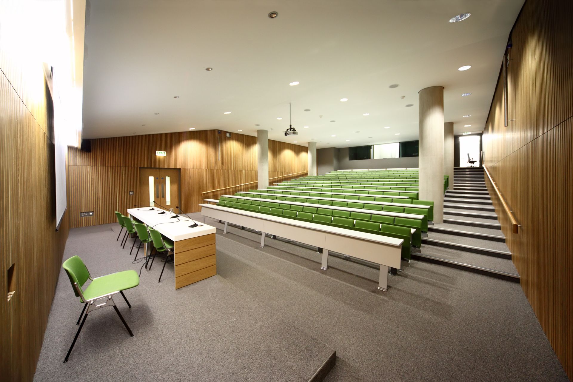 Empty Lecture Hall With Rows Of Green Seats, Light Wood Paneling, And A Table With Chairs In The Foreground — Rocky Commercial Cleaners In Berserker, QLD