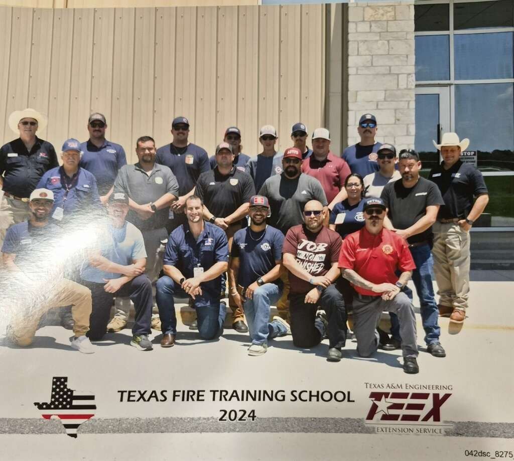 Texas Fire Training School 2024 group photo with firefighters standing and kneeling outdoors in front of a building
