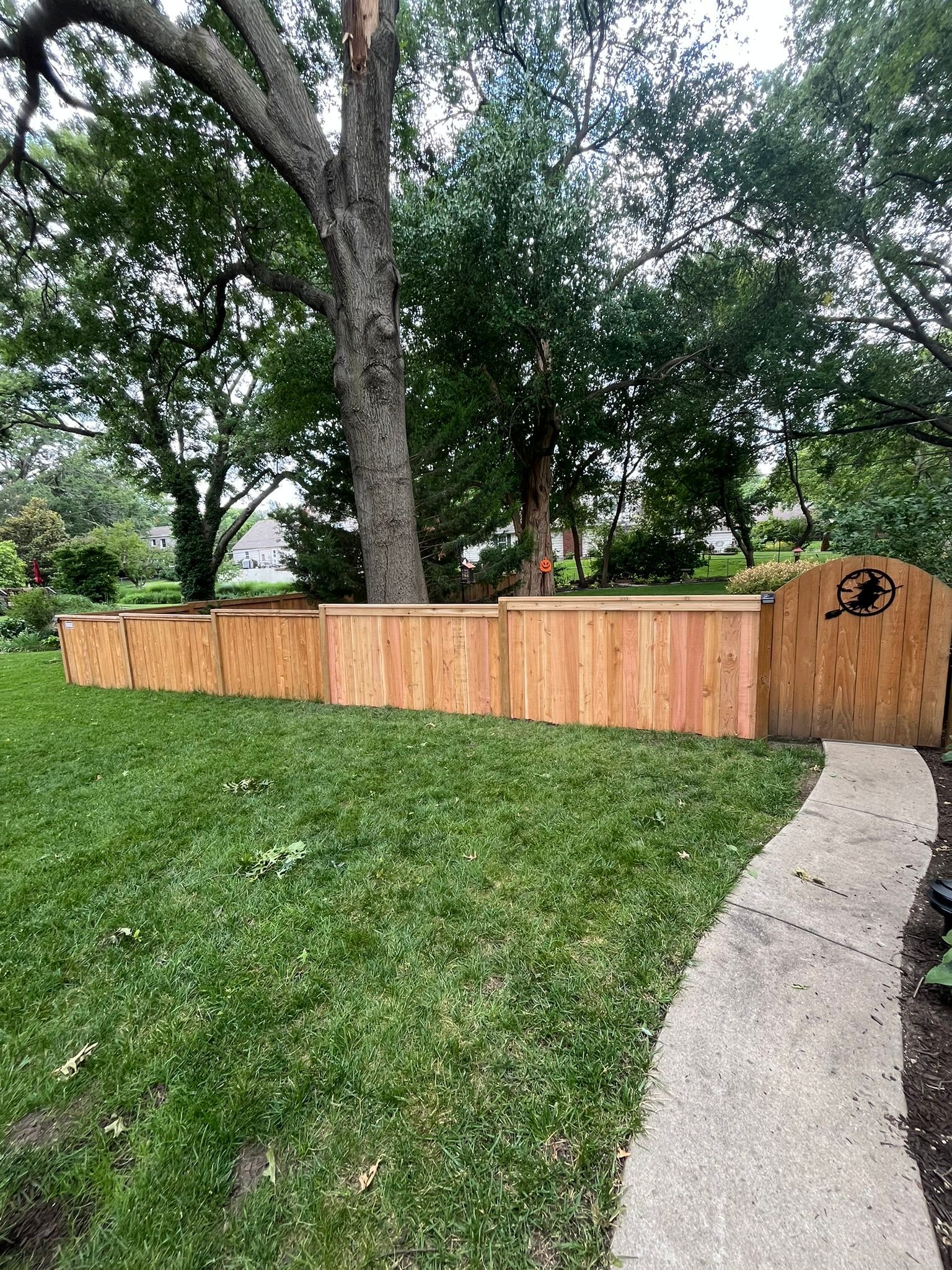 A wooden fence is sitting in the middle of a lush green yard.
