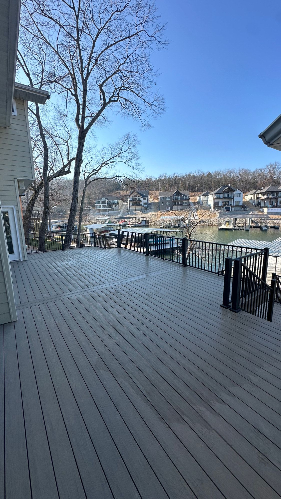 Snow-dusted wooden deck overlooking a calm marina under a clear blue sky