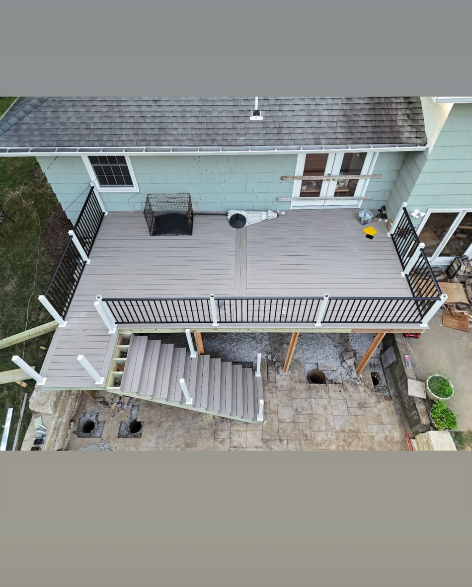A wooden deck with stairs and a pergola in the backyard of a house.
