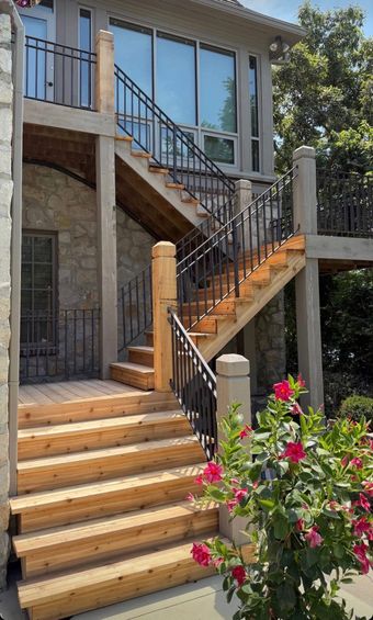 A wooden deck is in front of a brick house.