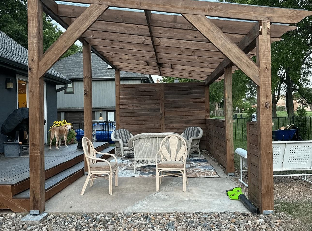 A wooden pergola with a table and chairs underneath it.