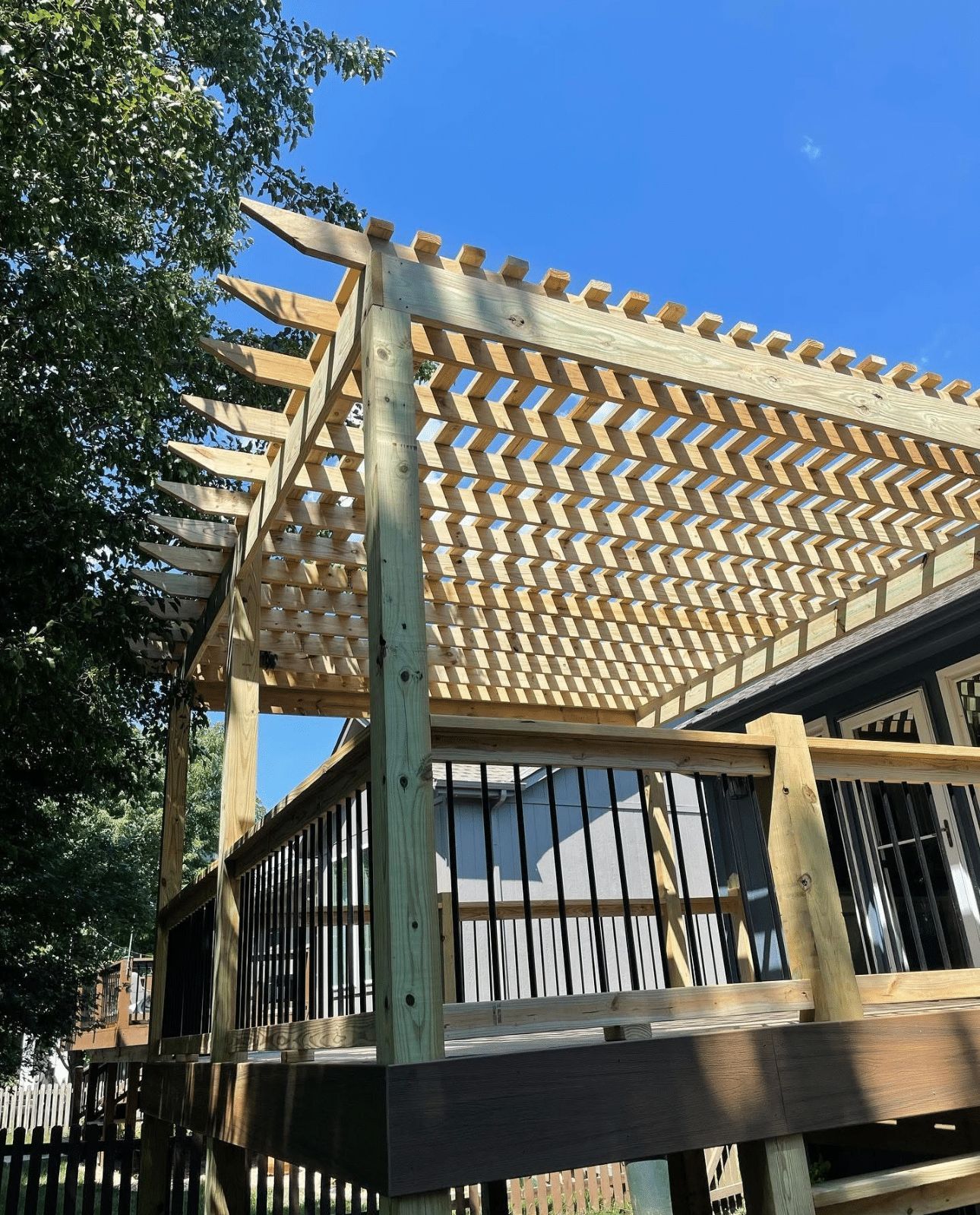 A wooden pergola is sitting on top of a wooden deck.