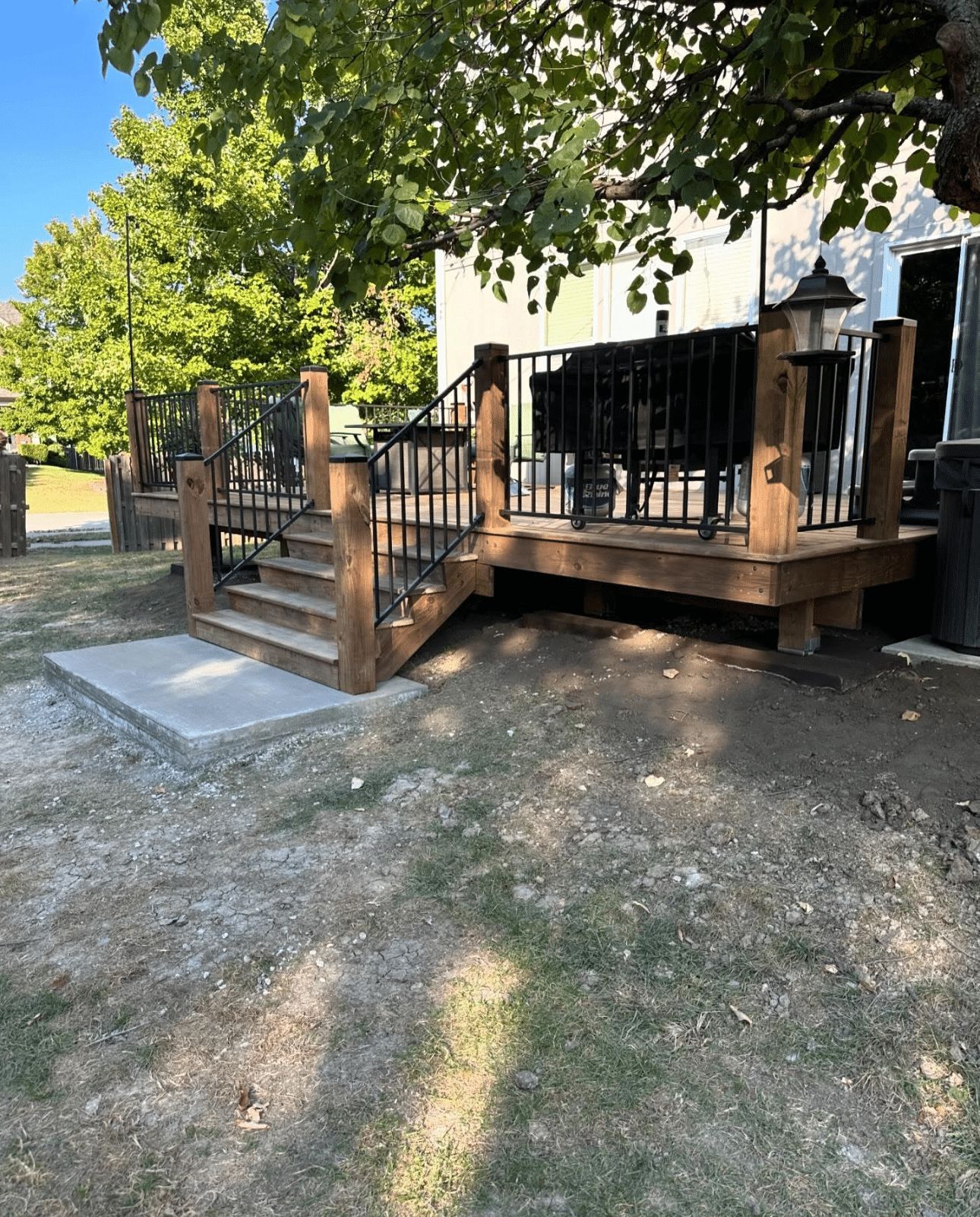 A wooden deck with stairs leading up to it in front of a house.