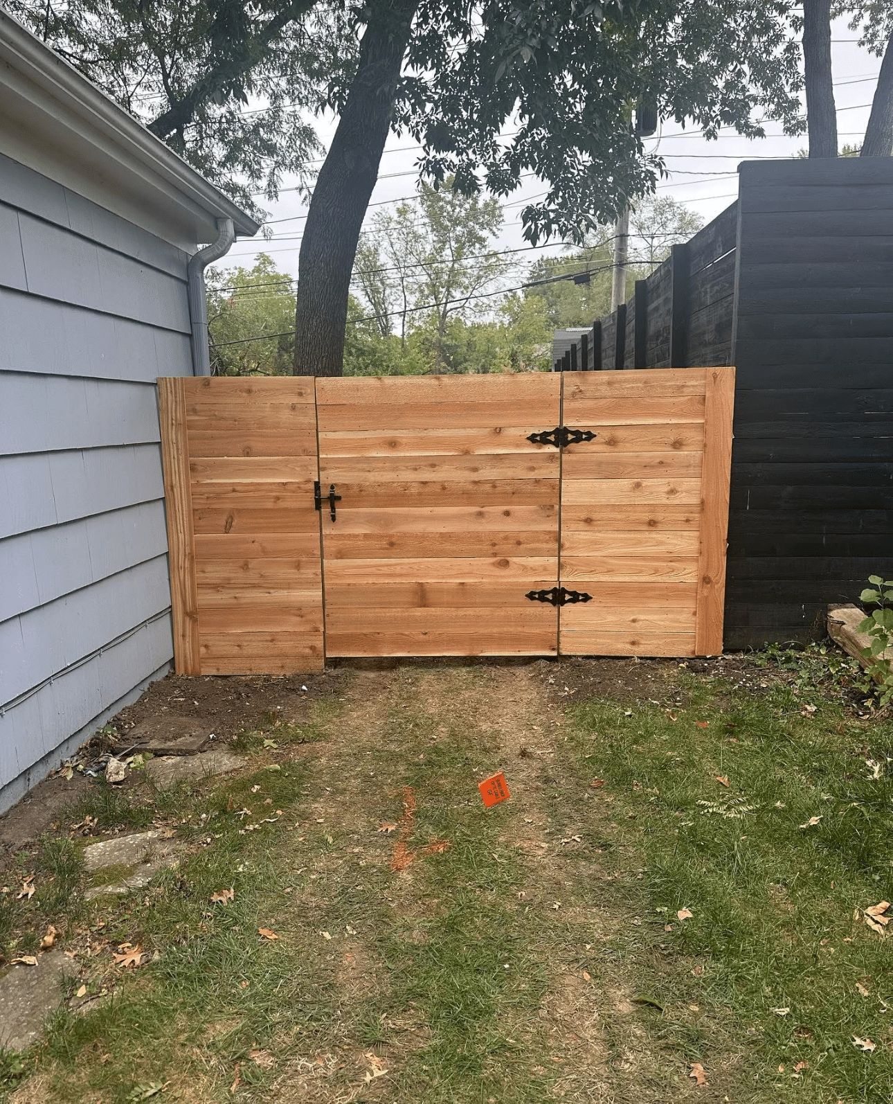 A wooden gate is in the backyard of a house.