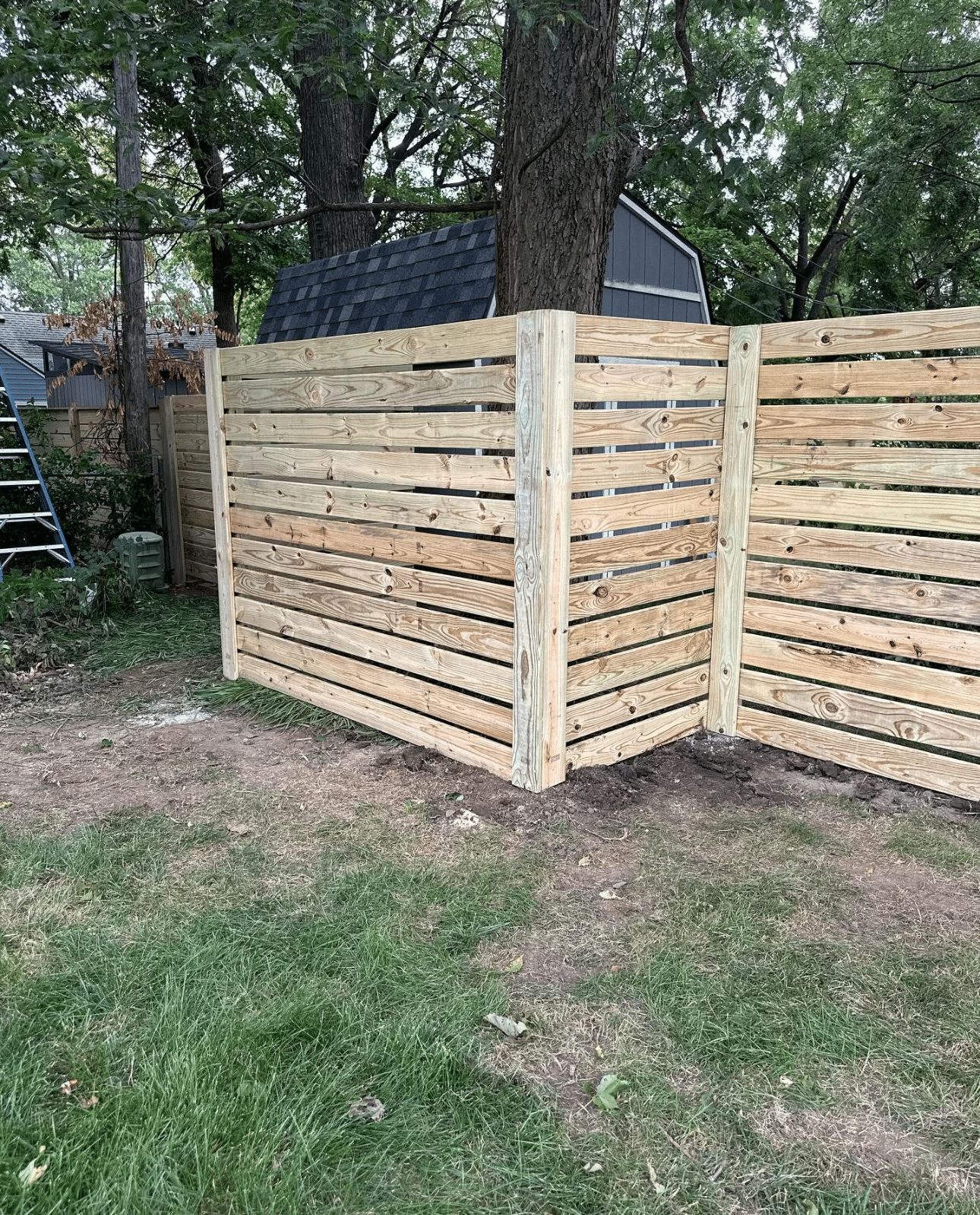 A wooden fence is sitting in the middle of a lush green yard.
