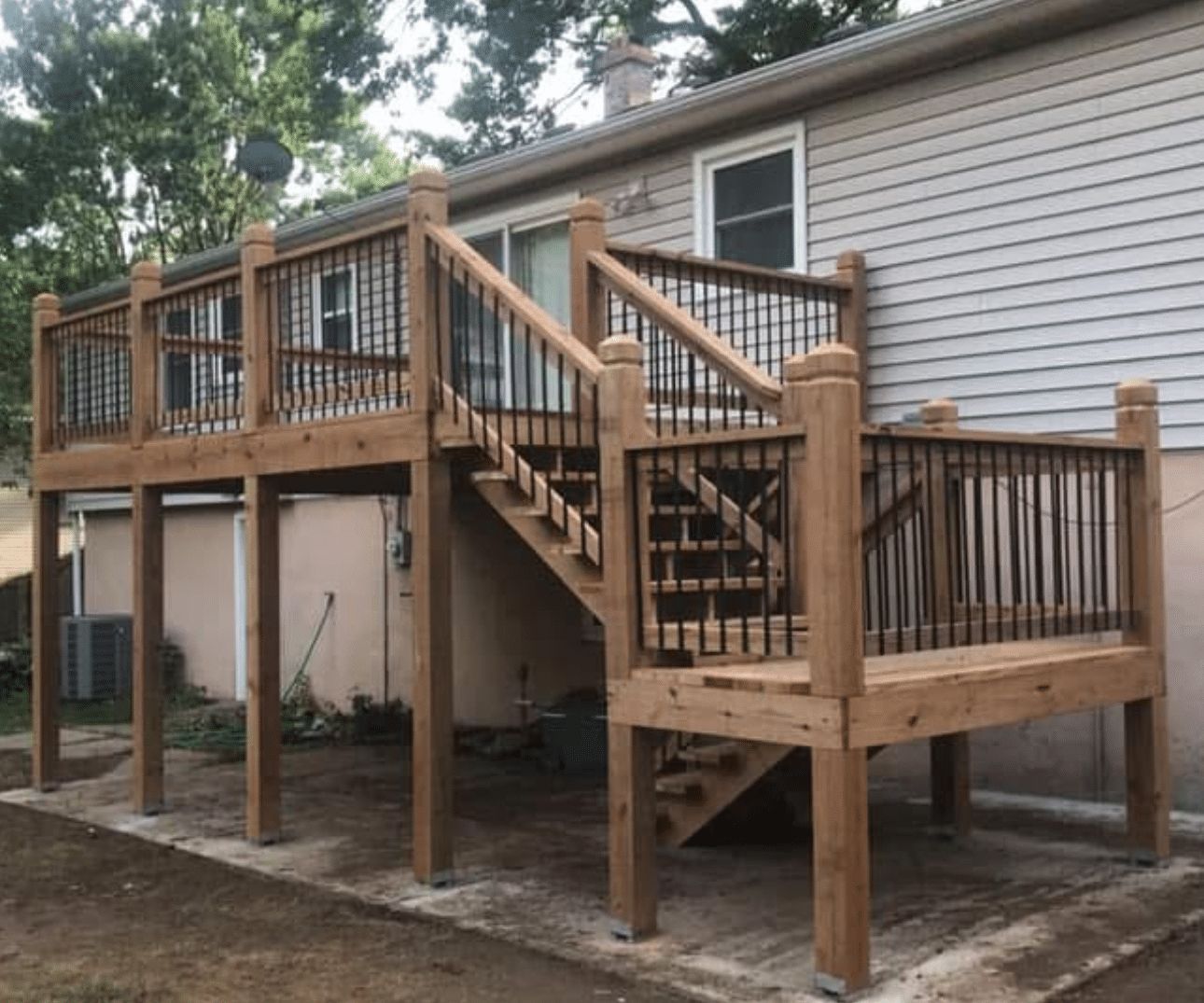 A wooden deck with stairs leading up to it is in front of a house.