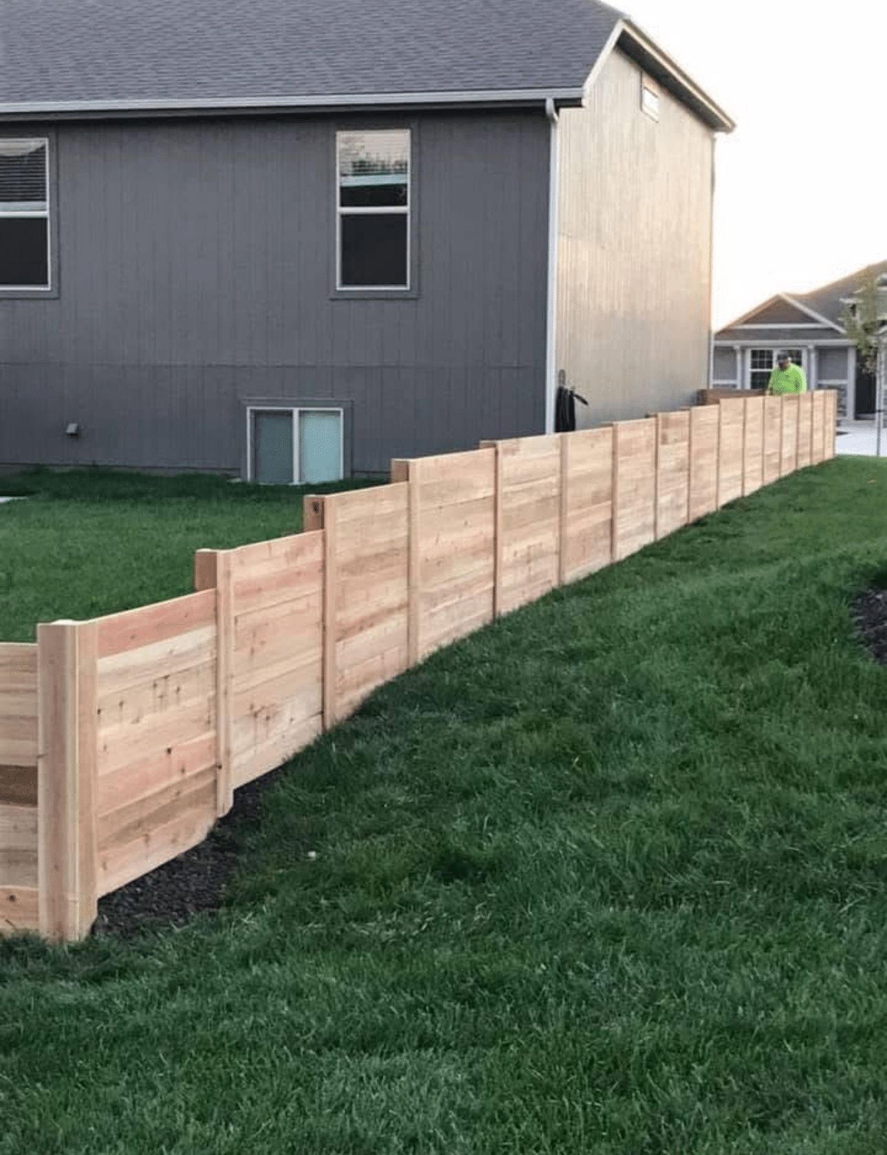 A wooden fence is sitting on top of a lush green lawn in front of a house.