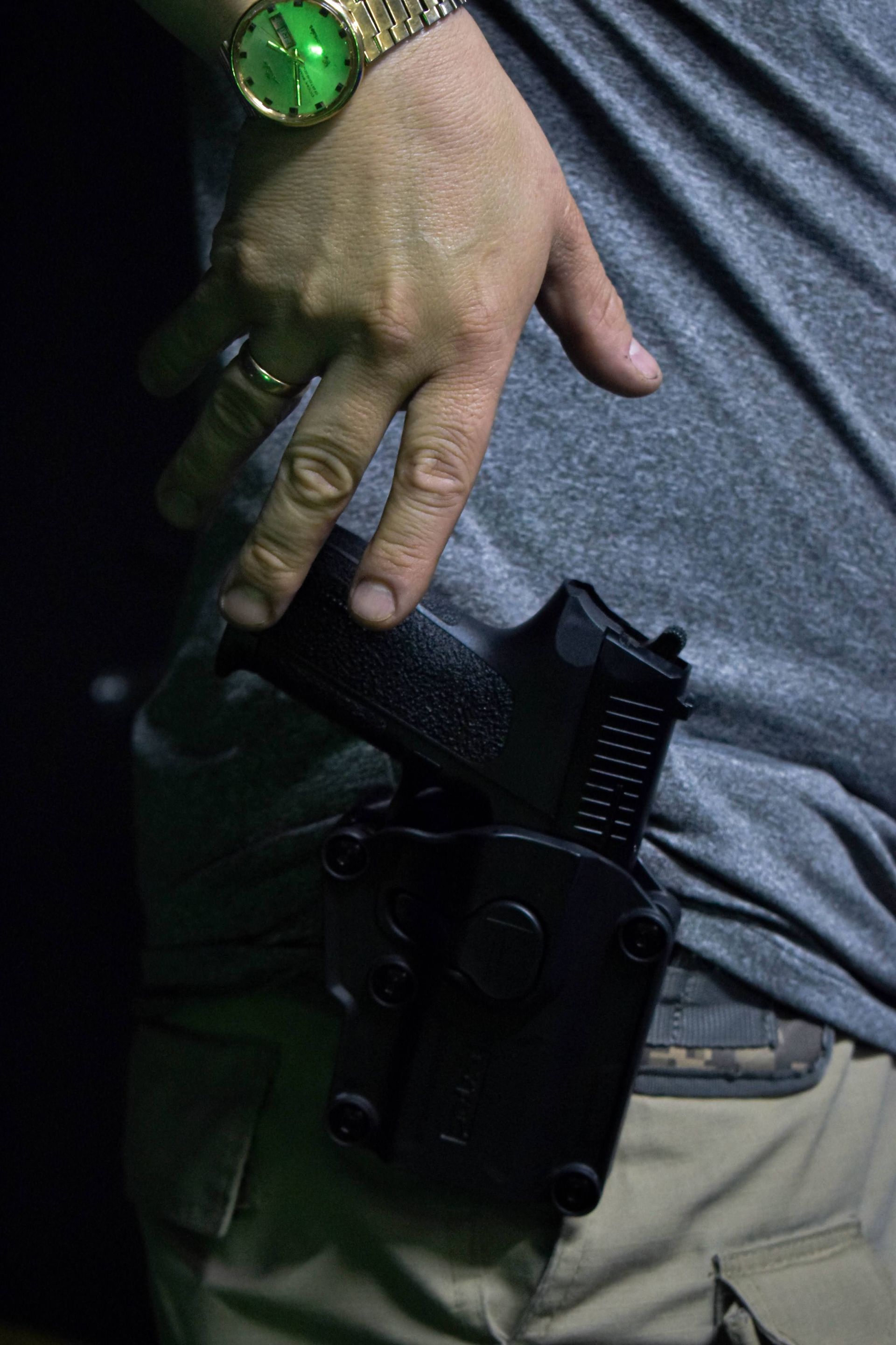 Arm extended, aiming a handgun in a dimly lit indoor range