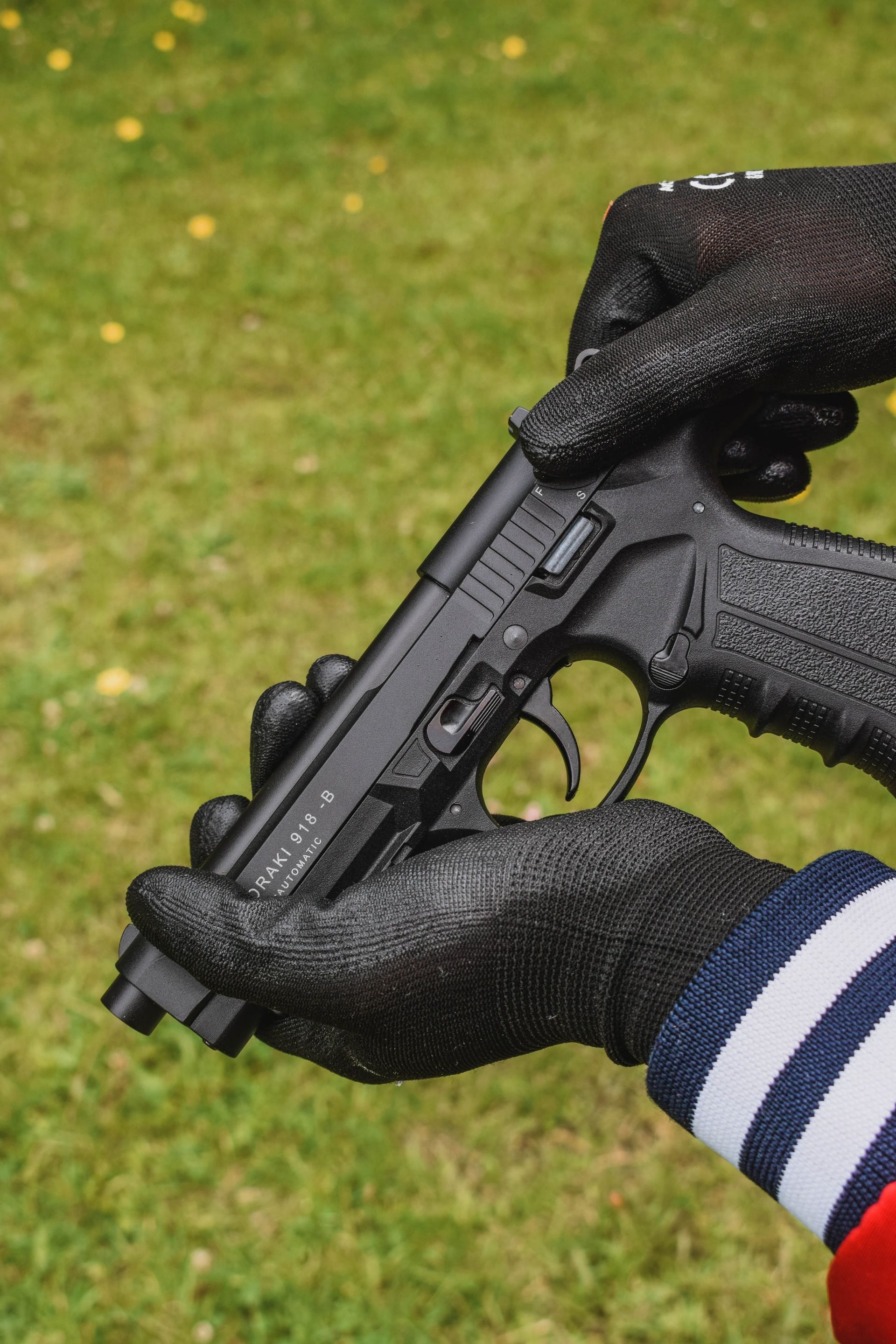 Person aiming a handgun at outdoor shooting range with tires as backstop