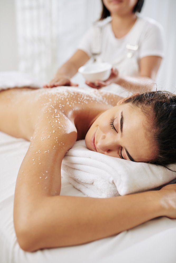 Beautician Applying Salt Scrub On Back Of Woman — VR Mobile Beauty Therapy In Oxenford QLD