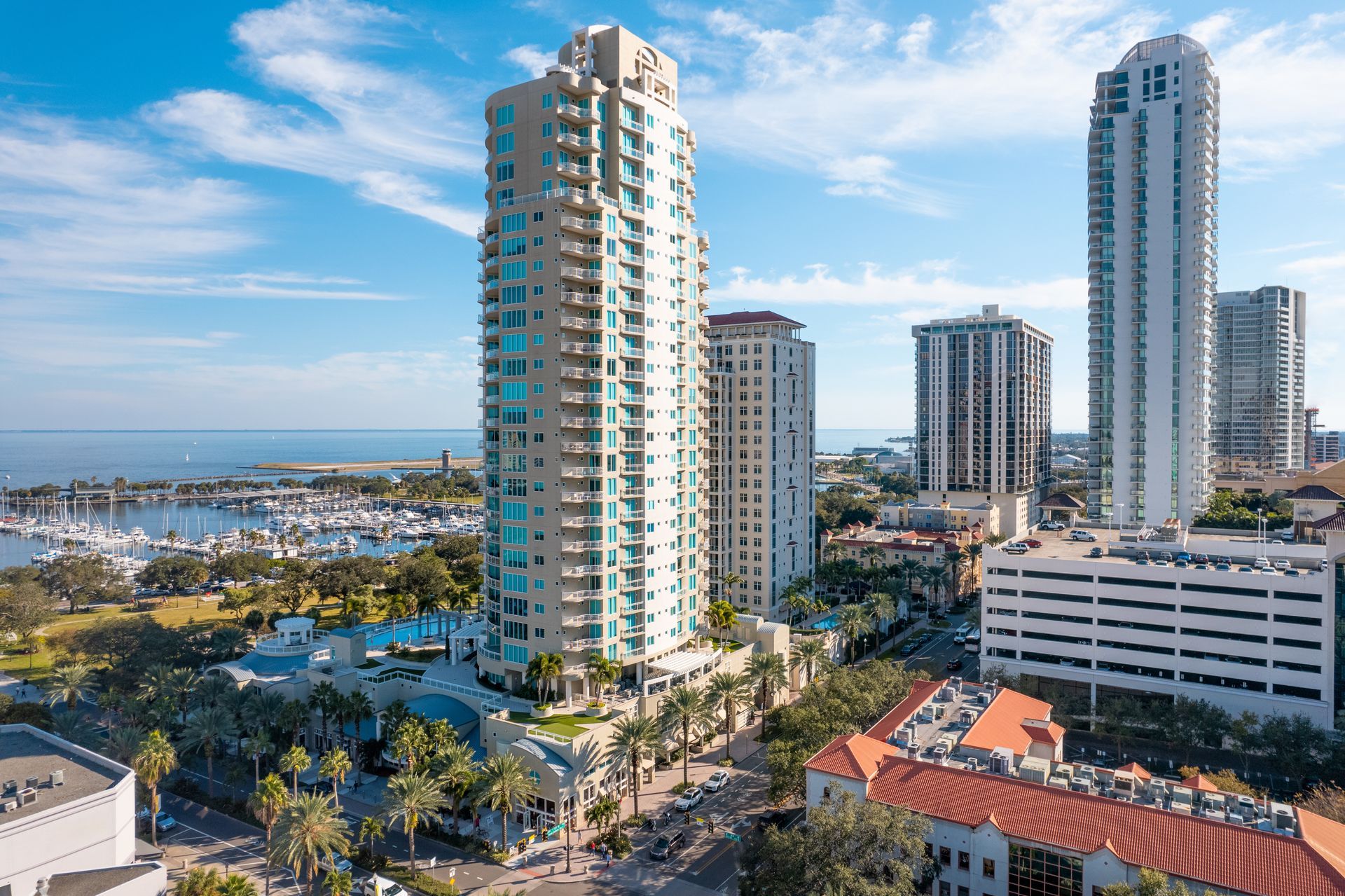 Coastal city skyline with tall modern high-rises, palm trees, and blue sky near the waterfront