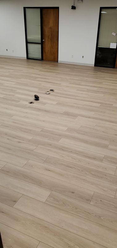 Empty room with light wood floor, two doors, and small objects scattered near the center.