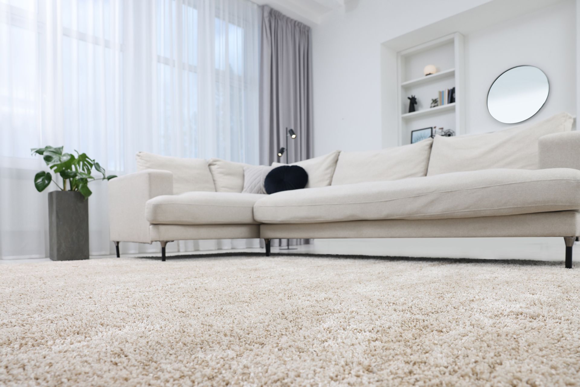 Bright minimalist living room with a cream sofa, white curtains, and a light shag rug