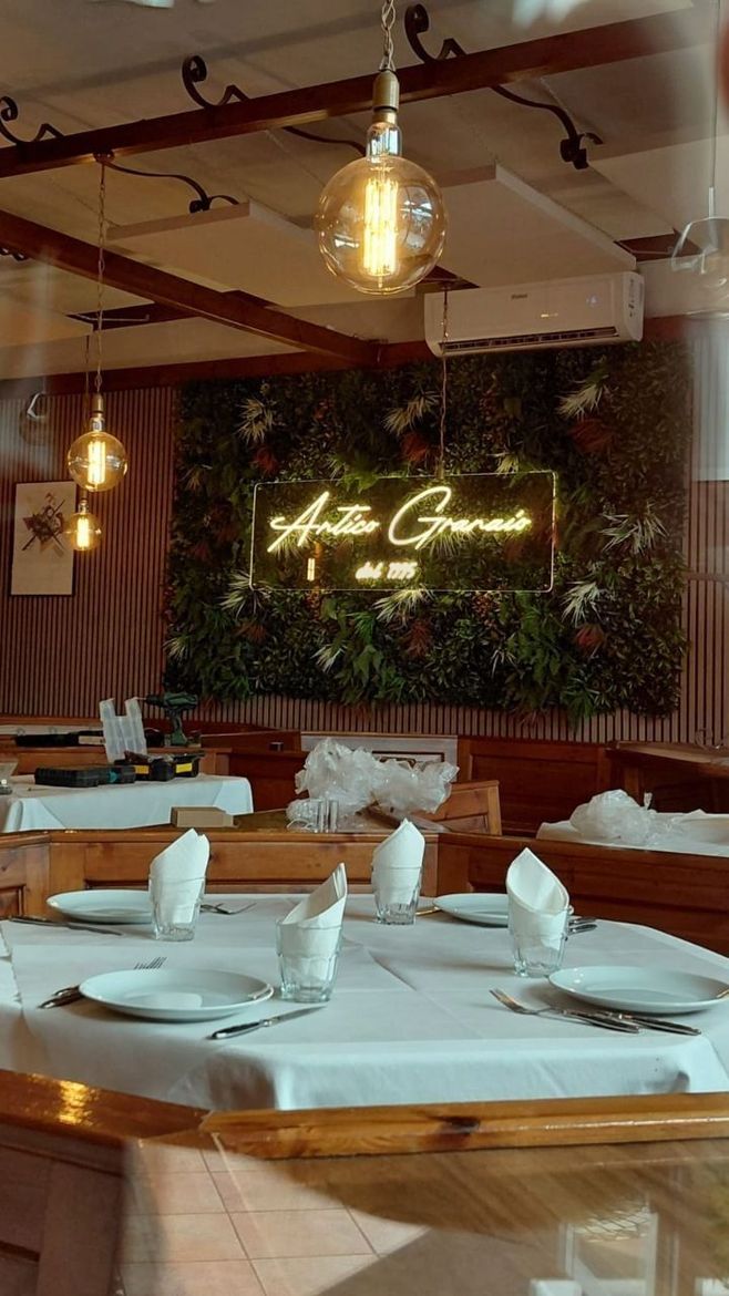 Insegna al neon con simboli luminosi di triangolo, cerchio, X e quadrato su un banco da lavoro.