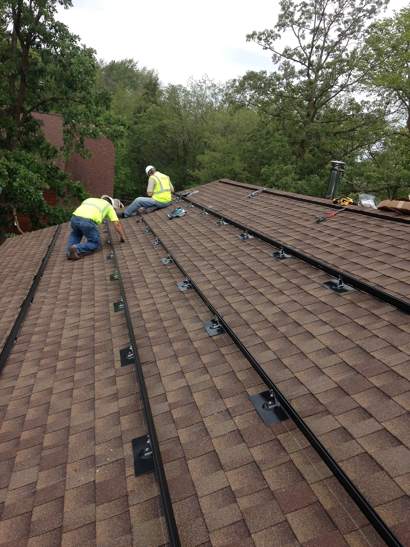 Two men are installing solar panels on the roof of a house.