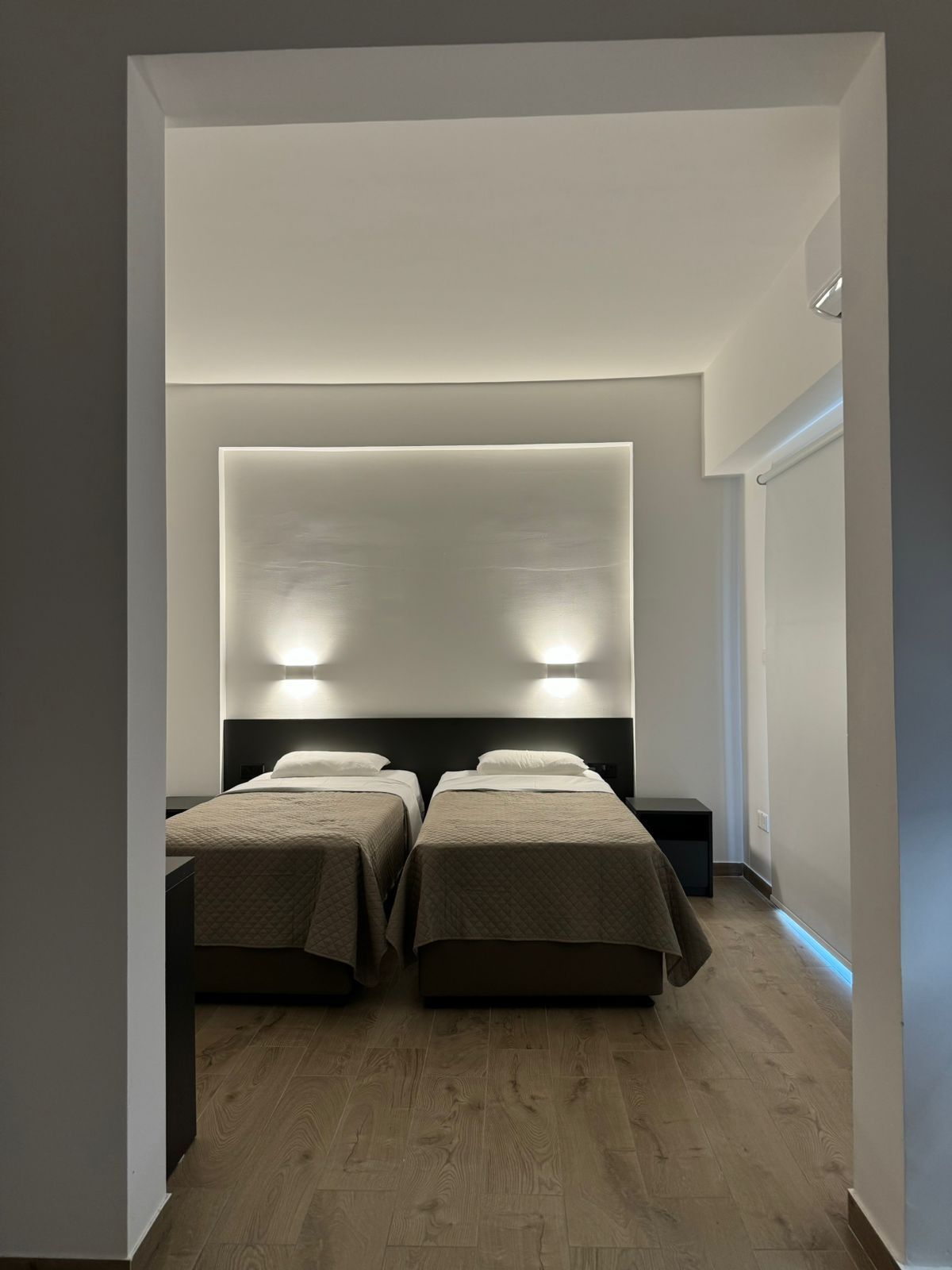A hotel room with two beds and a wooden floor