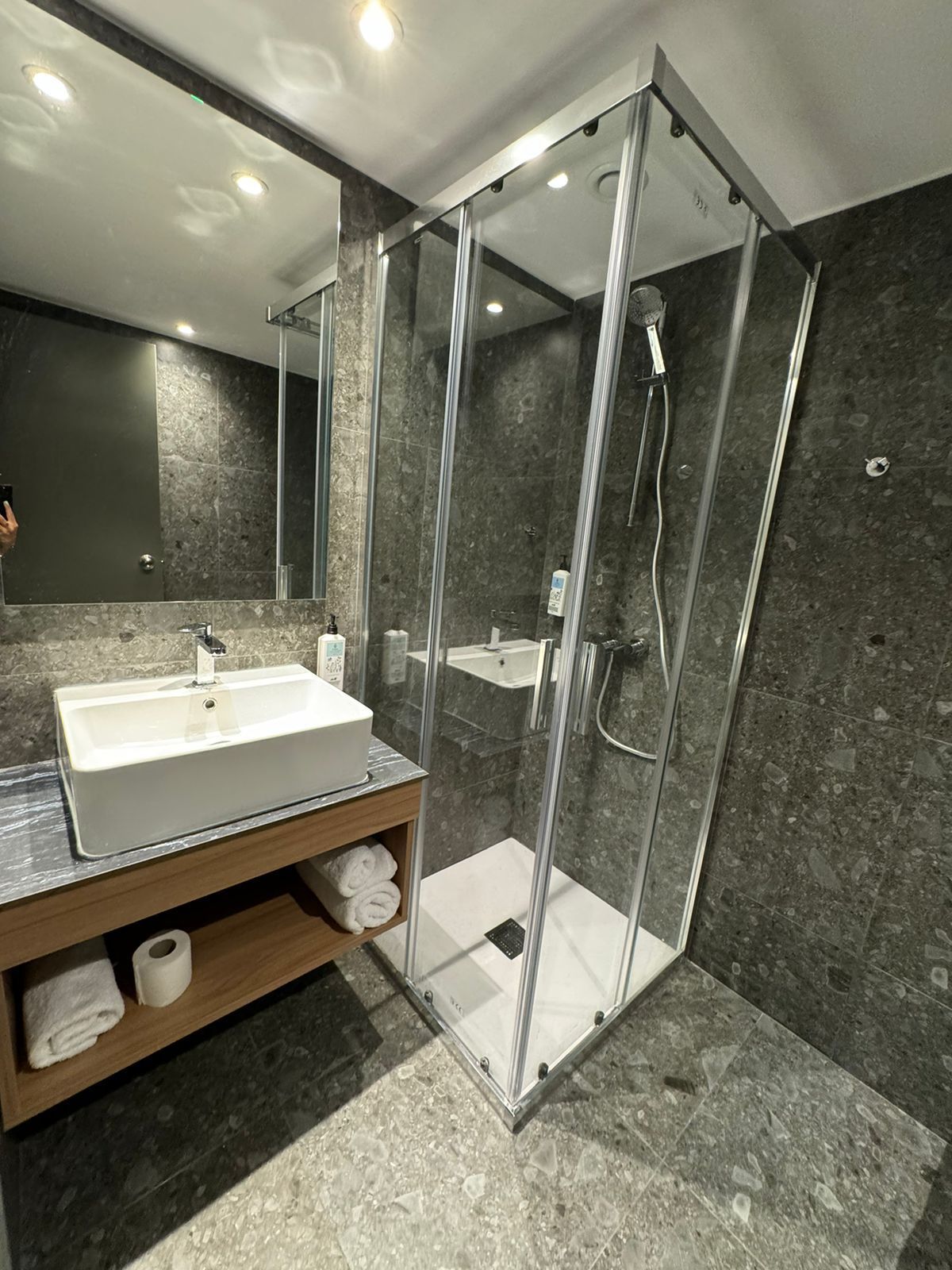 A bathroom with a sink , mirror and shower stall.