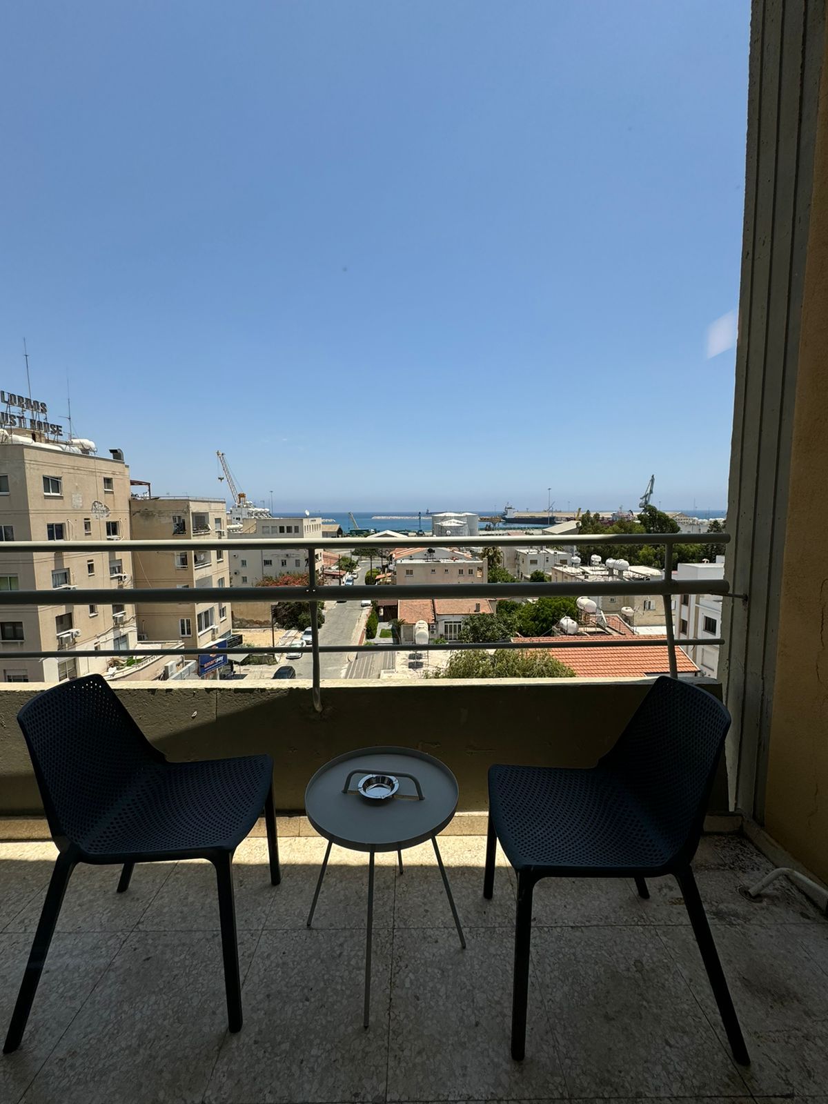 Two chairs and a table on a balcony overlooking a city