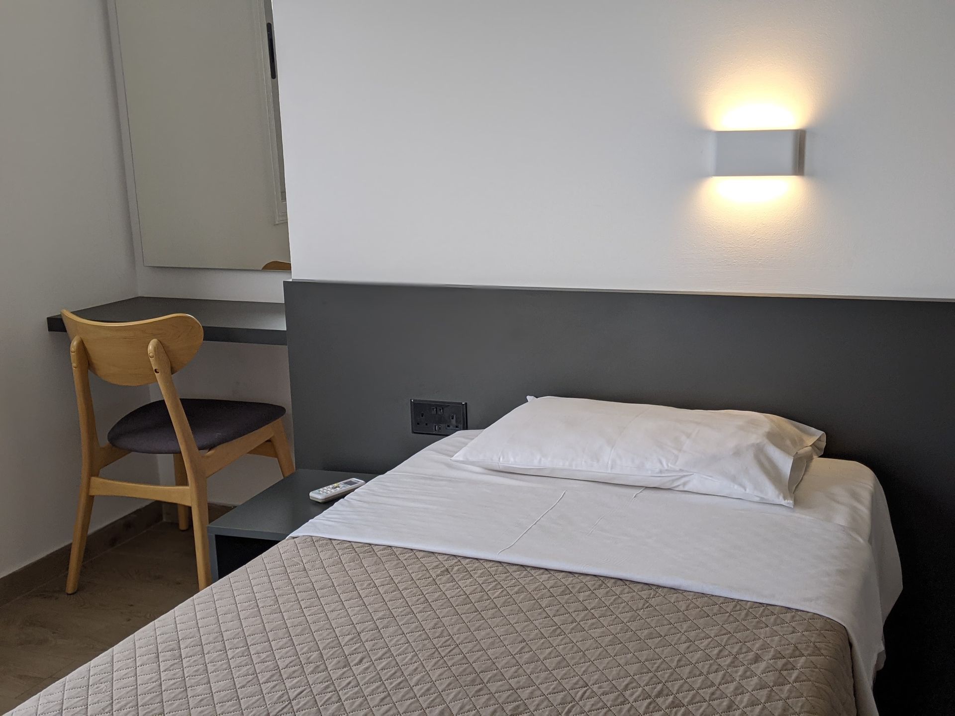 A hotel room with a single bed , chair and desk.
