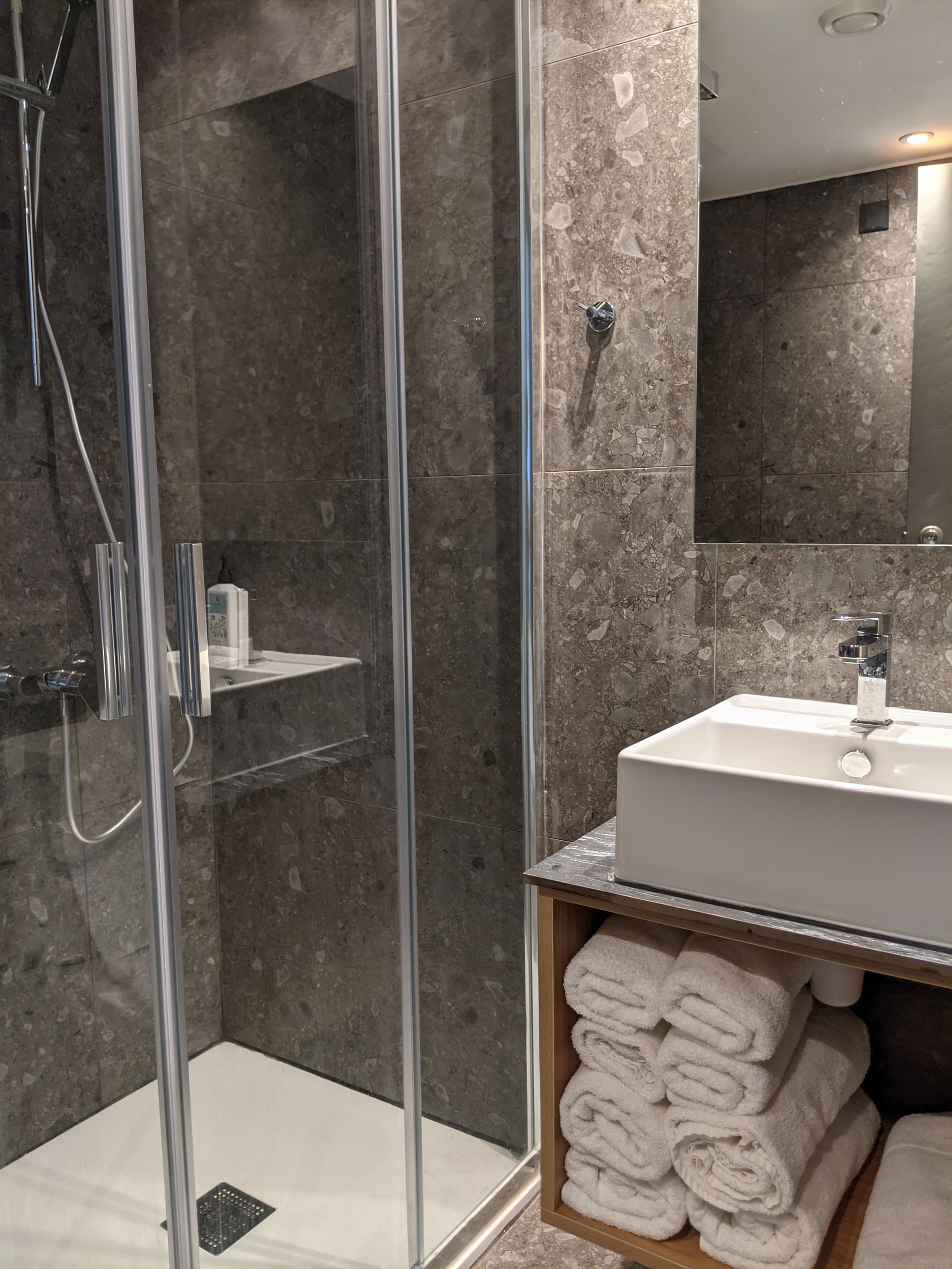 A bathroom with a sink , shower , and mirror.