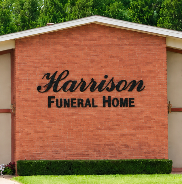 Harrison Funeral Home sign on a red brick building with green landscaping