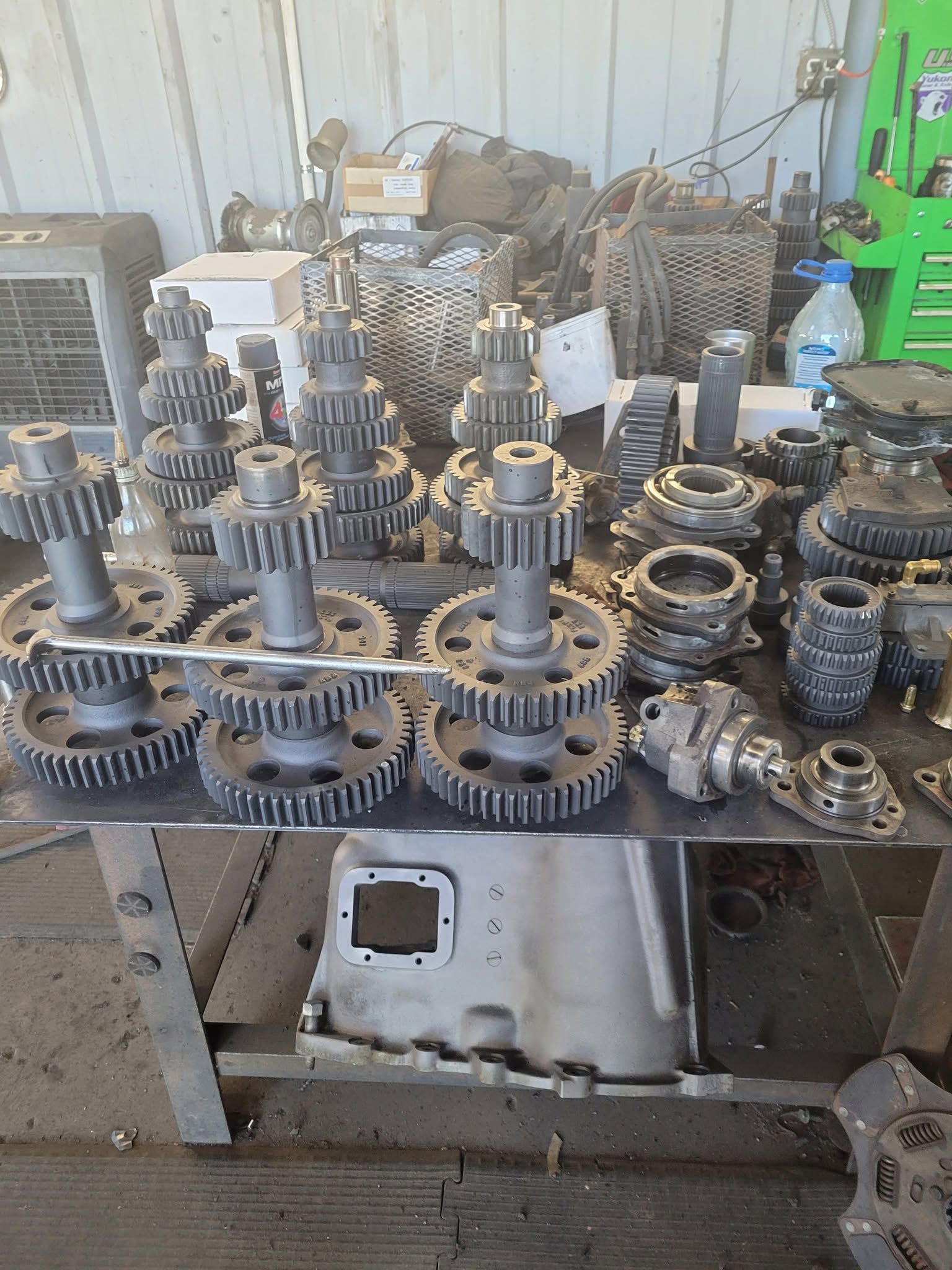 Assorted metal gears and mechanical parts stacked on a workbench in an industrial workshop.