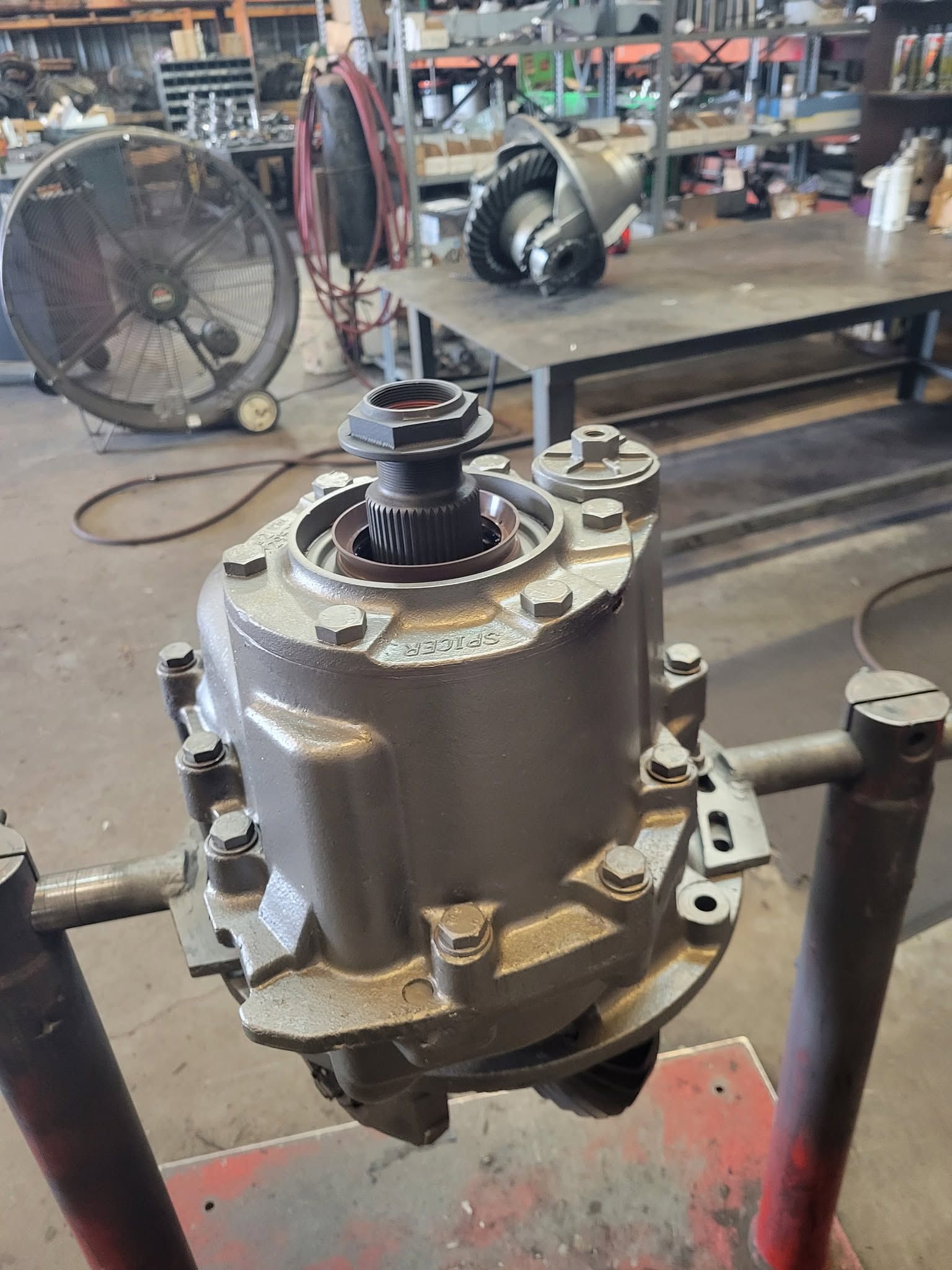 Industrial machinery part on a workshop floor, with a large metal housing and exposed gears.