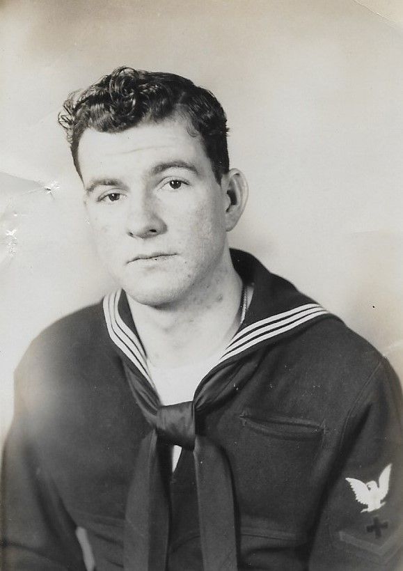 Portrait of a sailor in a dark navy uniform against a plain background
