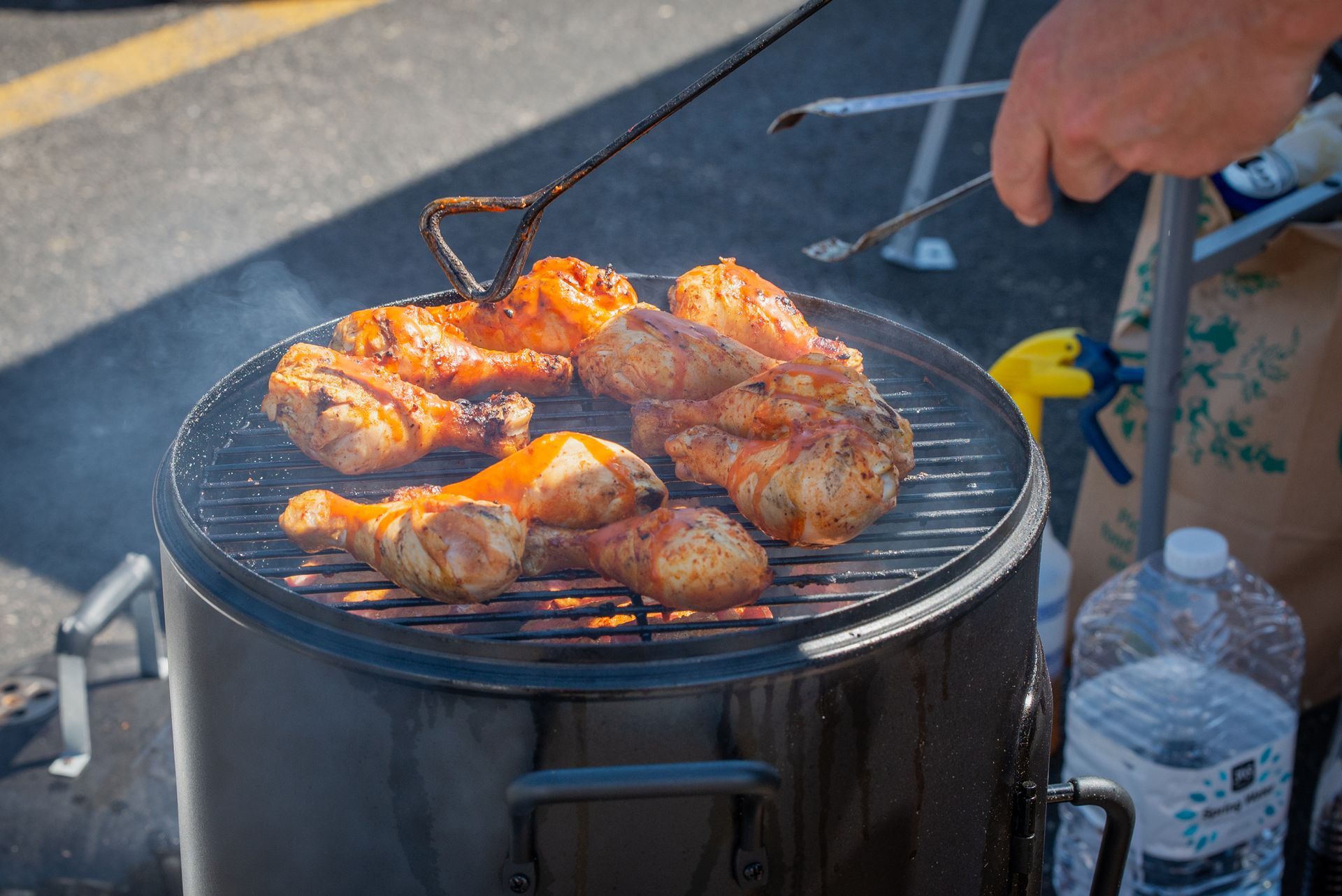 A person is cooking chicken on a grill.