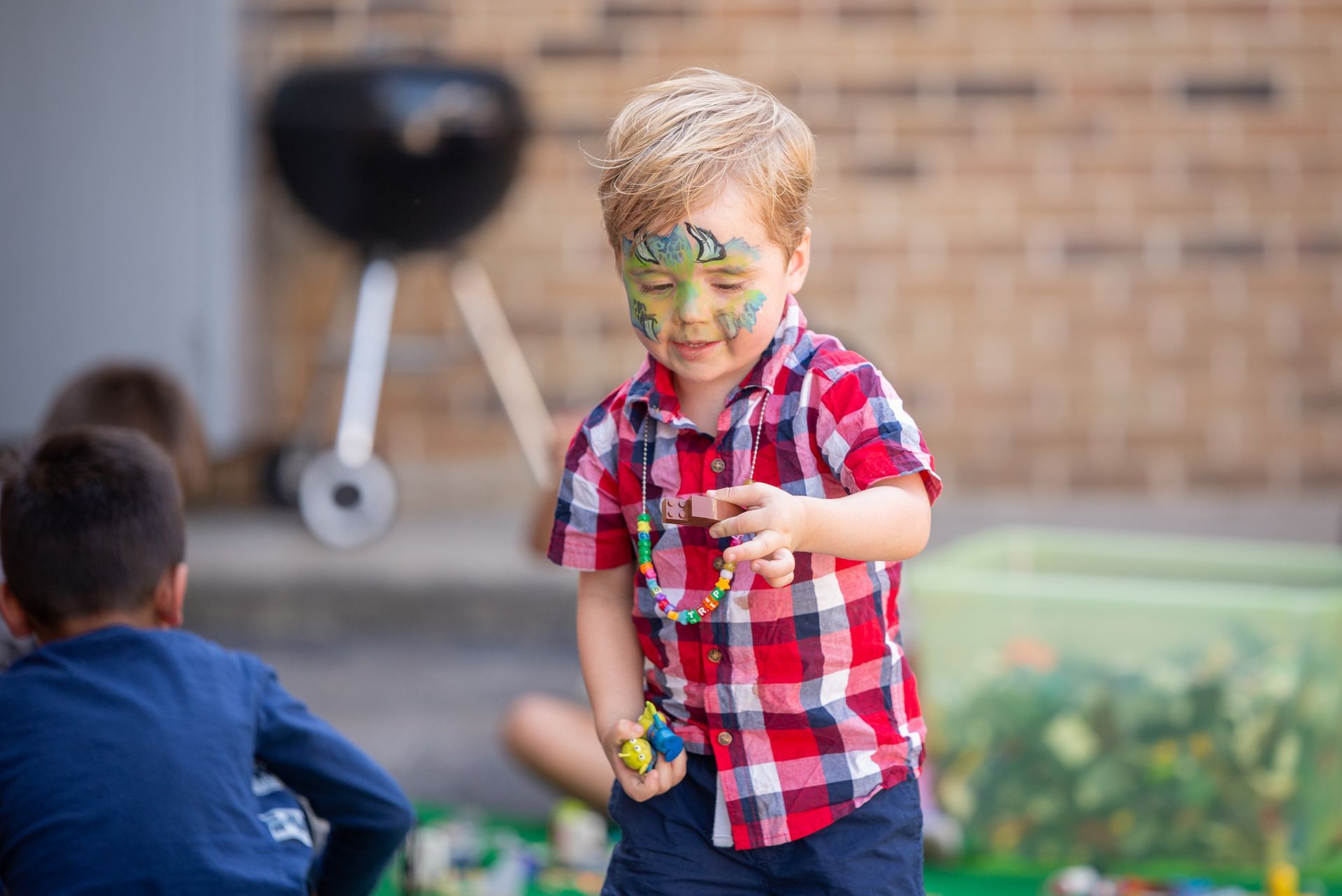A young boy with his face painted is playing with toys.