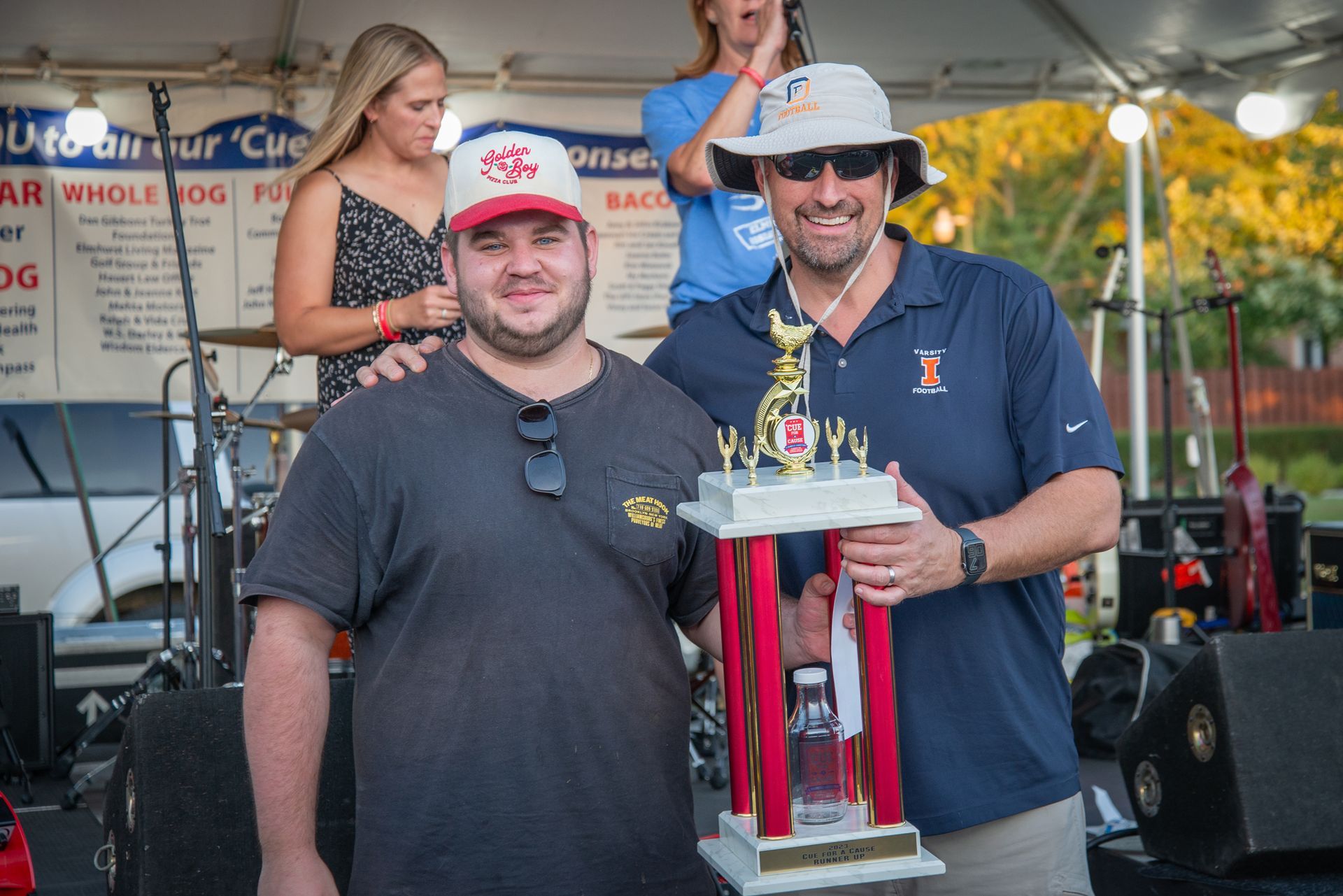 Two men are standing next to each other holding a trophy.