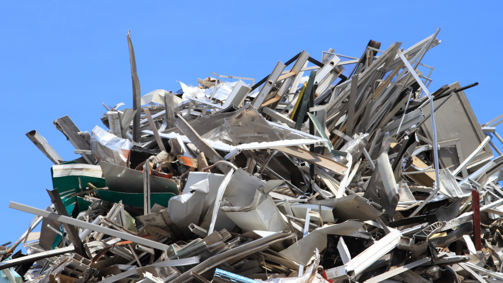 Pile of construction debris and scrap wood against a clear blue sky