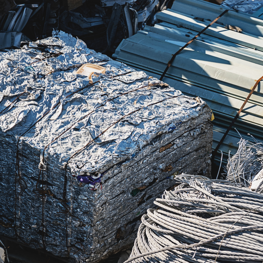 Stacked compressed metal scrap bales with coiled wire in an industrial yard