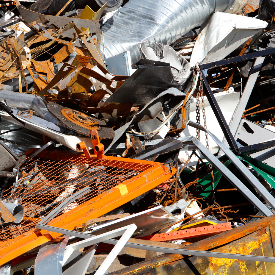 Pile of twisted metal and debris, including orange and white scraps, in a junkyard or demolition site