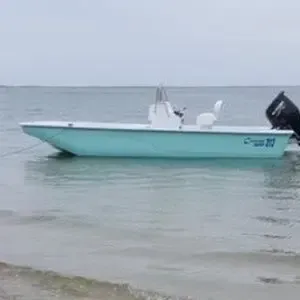 Light blue fishing boat floating on calm water near a sandy shore