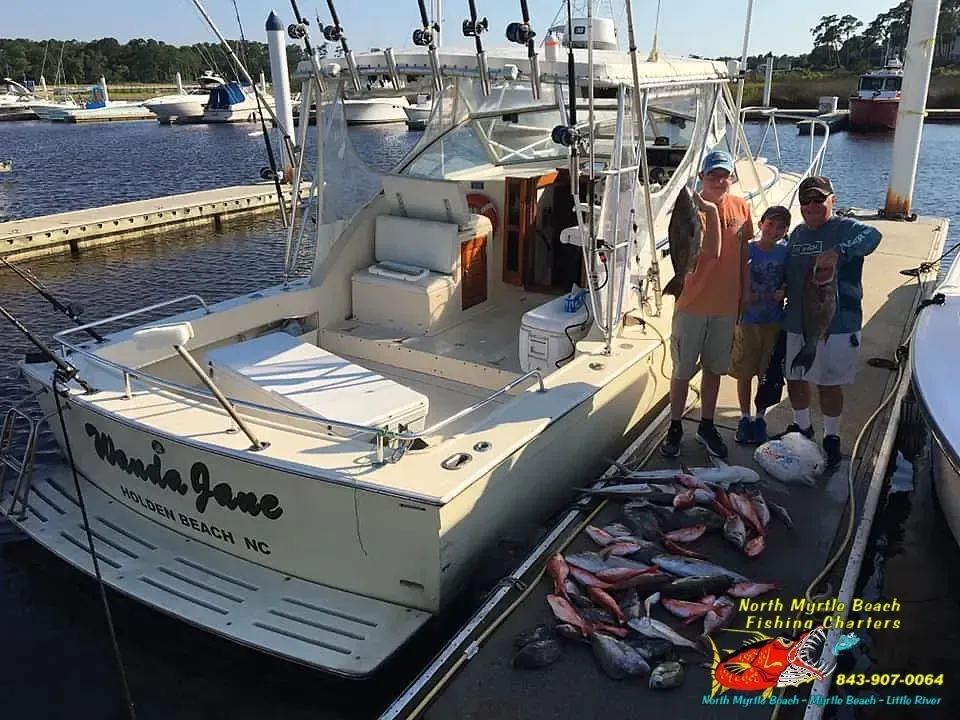 Fishing boat at dock with several people and a large pile of caught fish on the deck