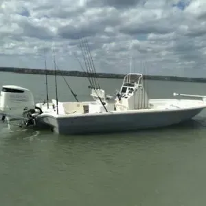 White fishing boat with outboard motor and fishing rods on calm water under cloudy skies
