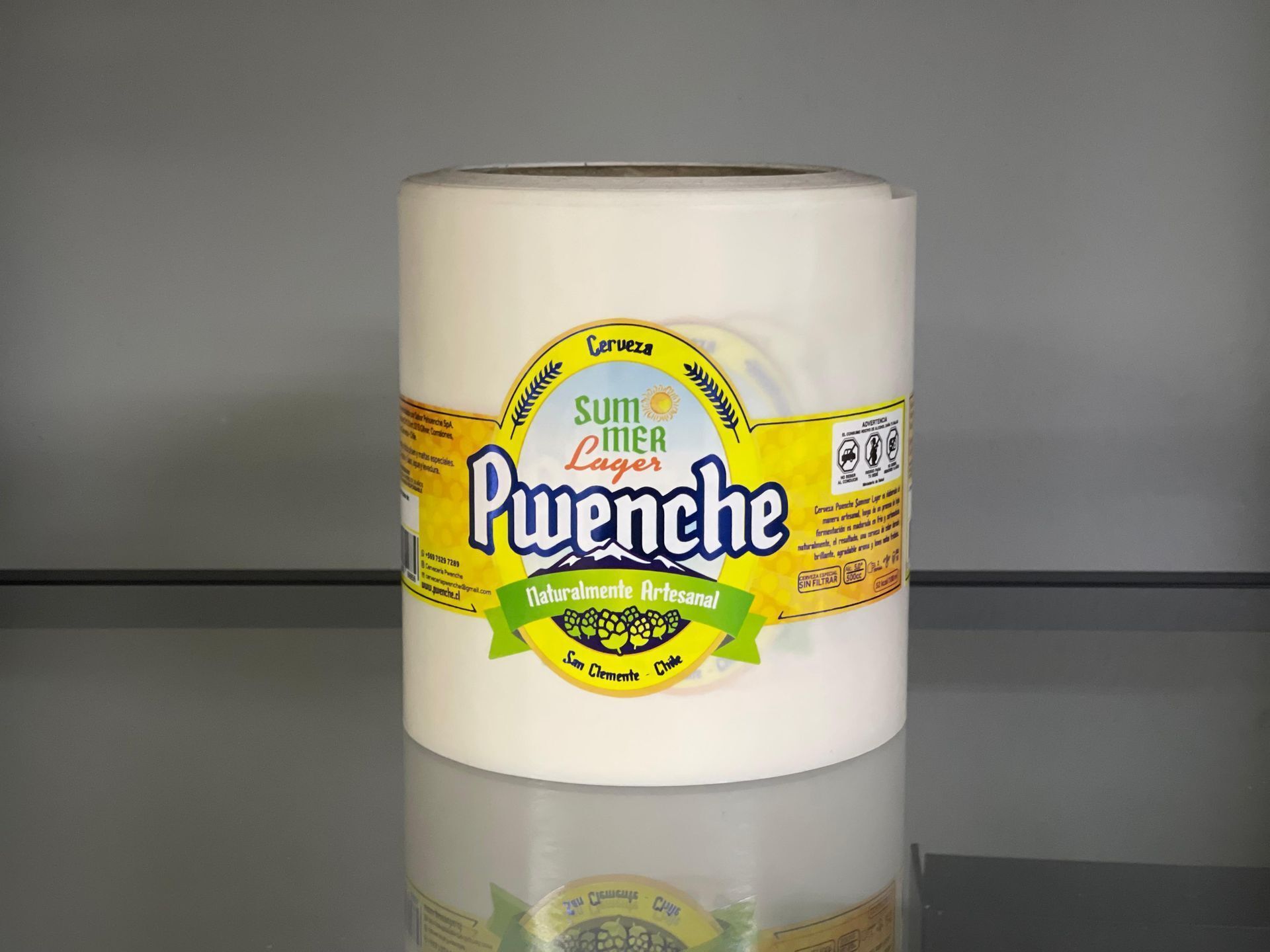 Un recipiente blanco con una etiqueta amarilla que dice “Puwenche” sobre una superficie reflectante.