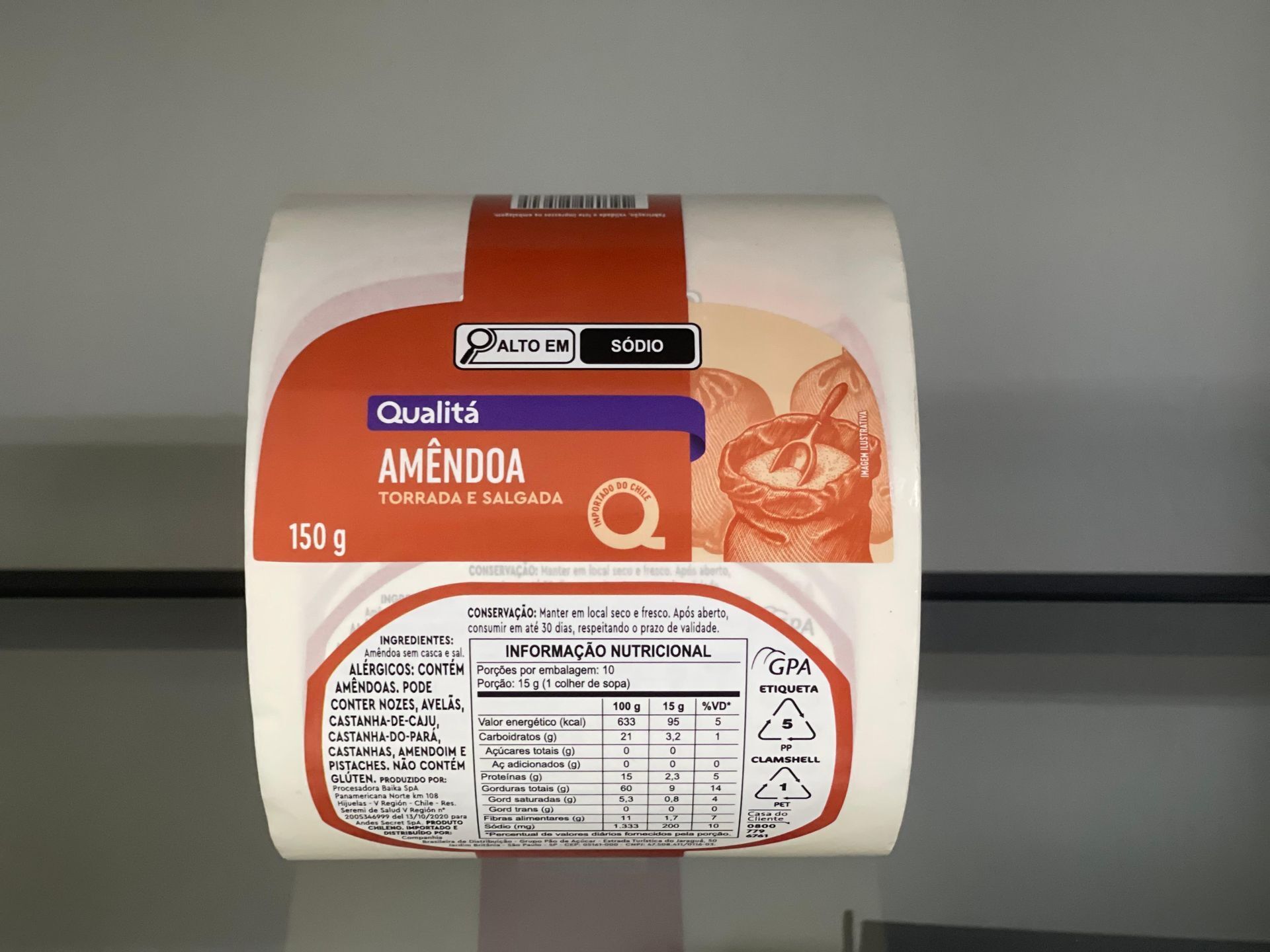 Rollo de envases de alimentos blancos y naranjas con una etiqueta, centrado en un estante gris.