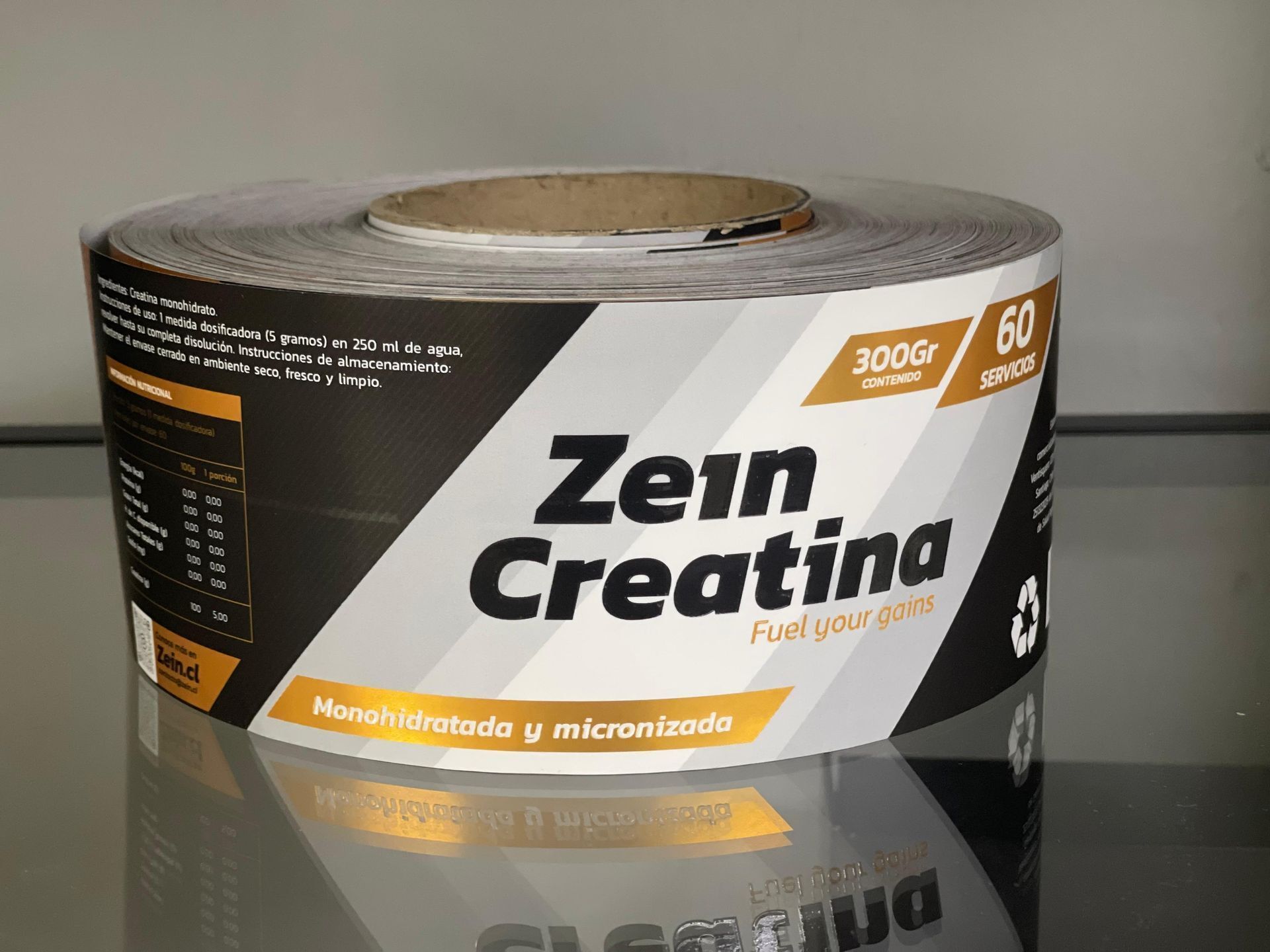 Envase del suplemento Zem Creatina sobre una superficie reflectante, etiqueta en blanco y negro con detalles en naranja.