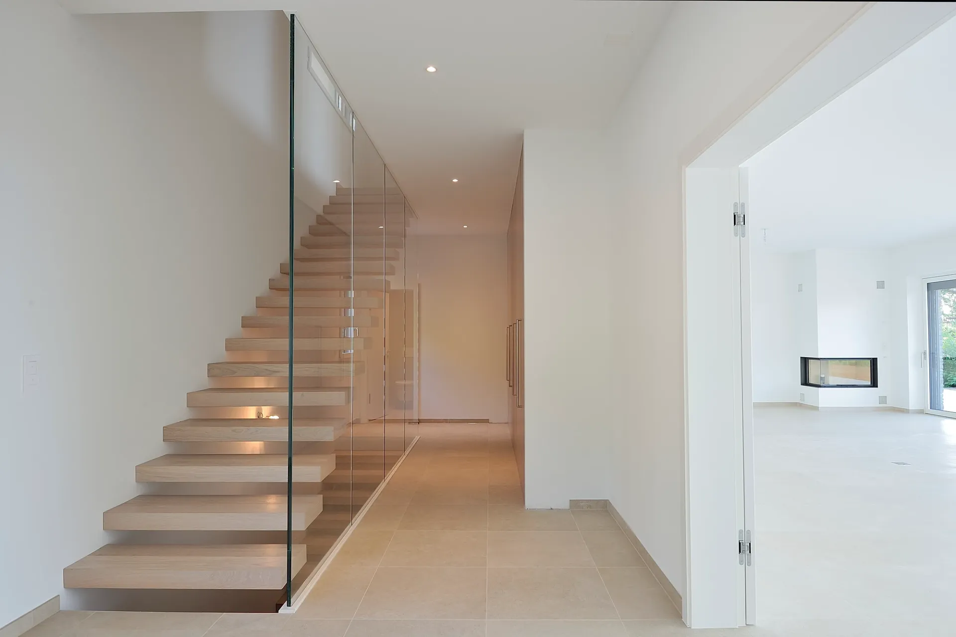 Un couloir vide avec un escalier et une rampe en verre.